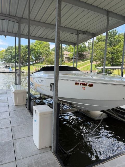 A white boat docked in a covered area, surrounded by water and trees.