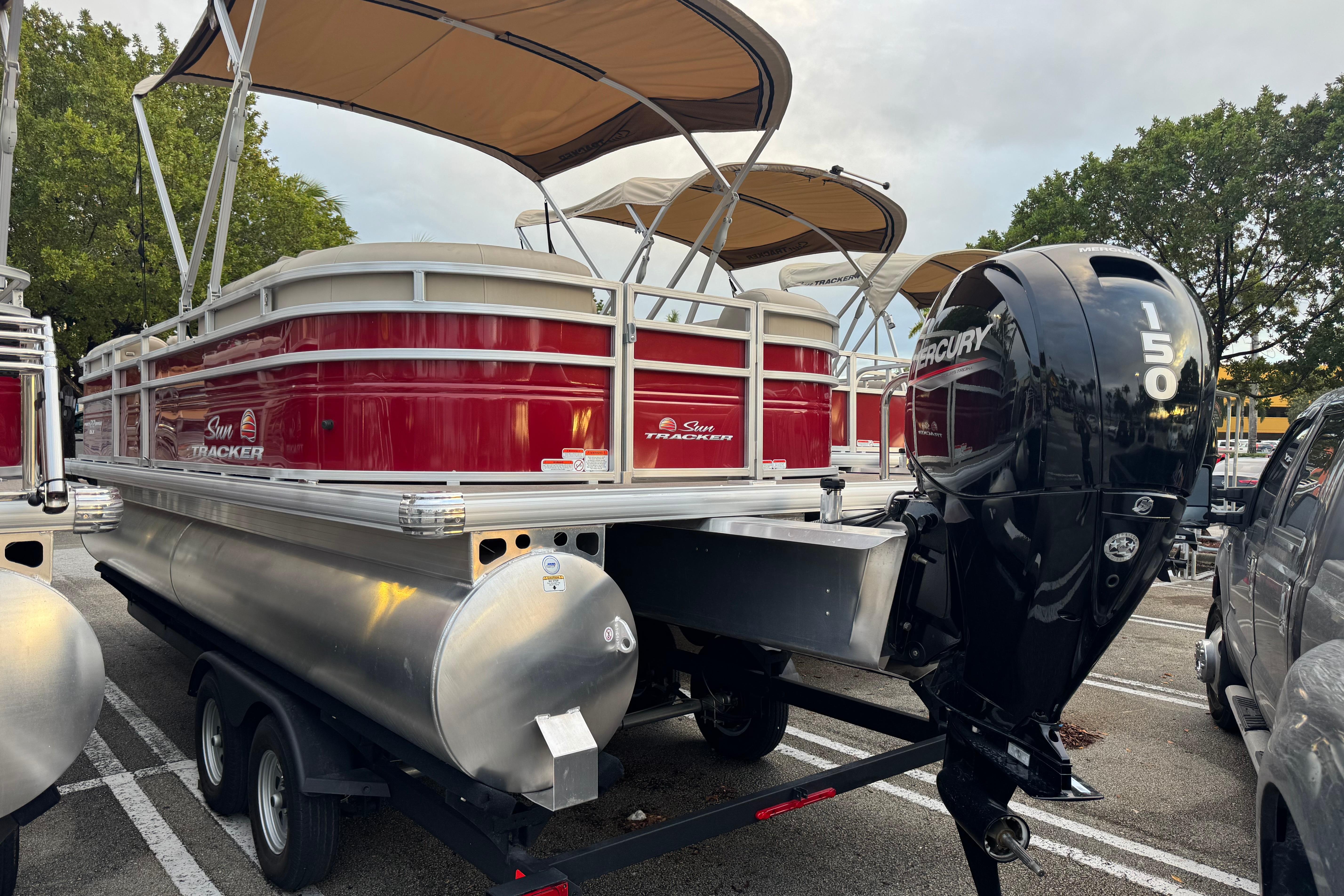 2025 Sun Tracker Party Barge 22 DLX pontoon boat with Mercury 150 engine in parking lot.