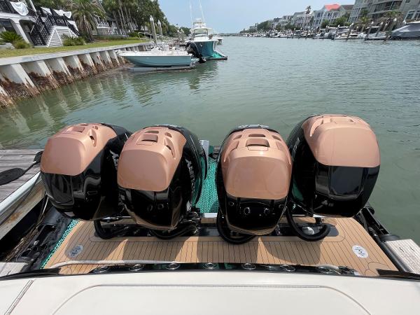 2020 Scout 420 LXF boat with four powerful outboard engines docked in a scenic marina.