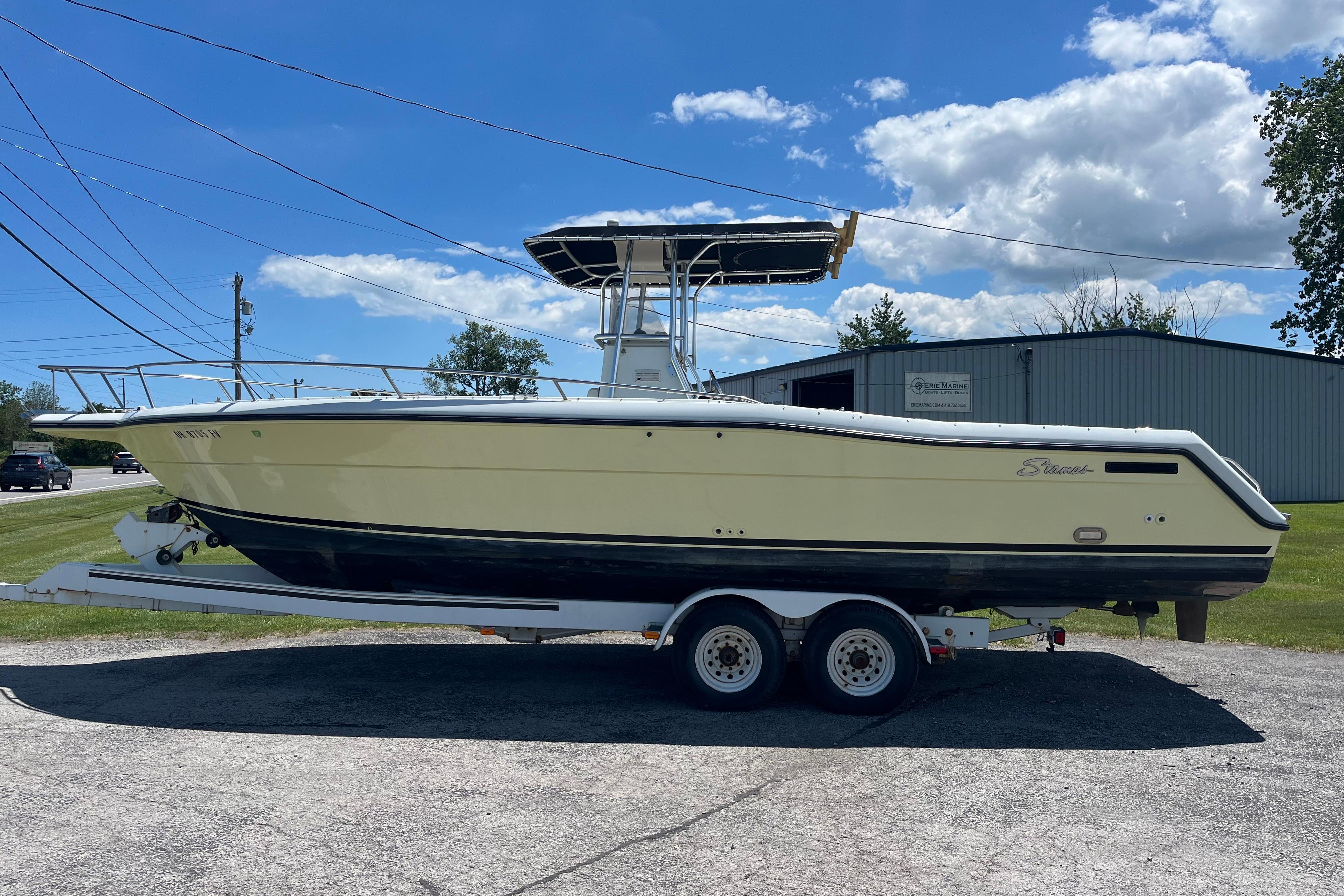 1997 Stamas boat on trailer under blue sky, parked near a building.