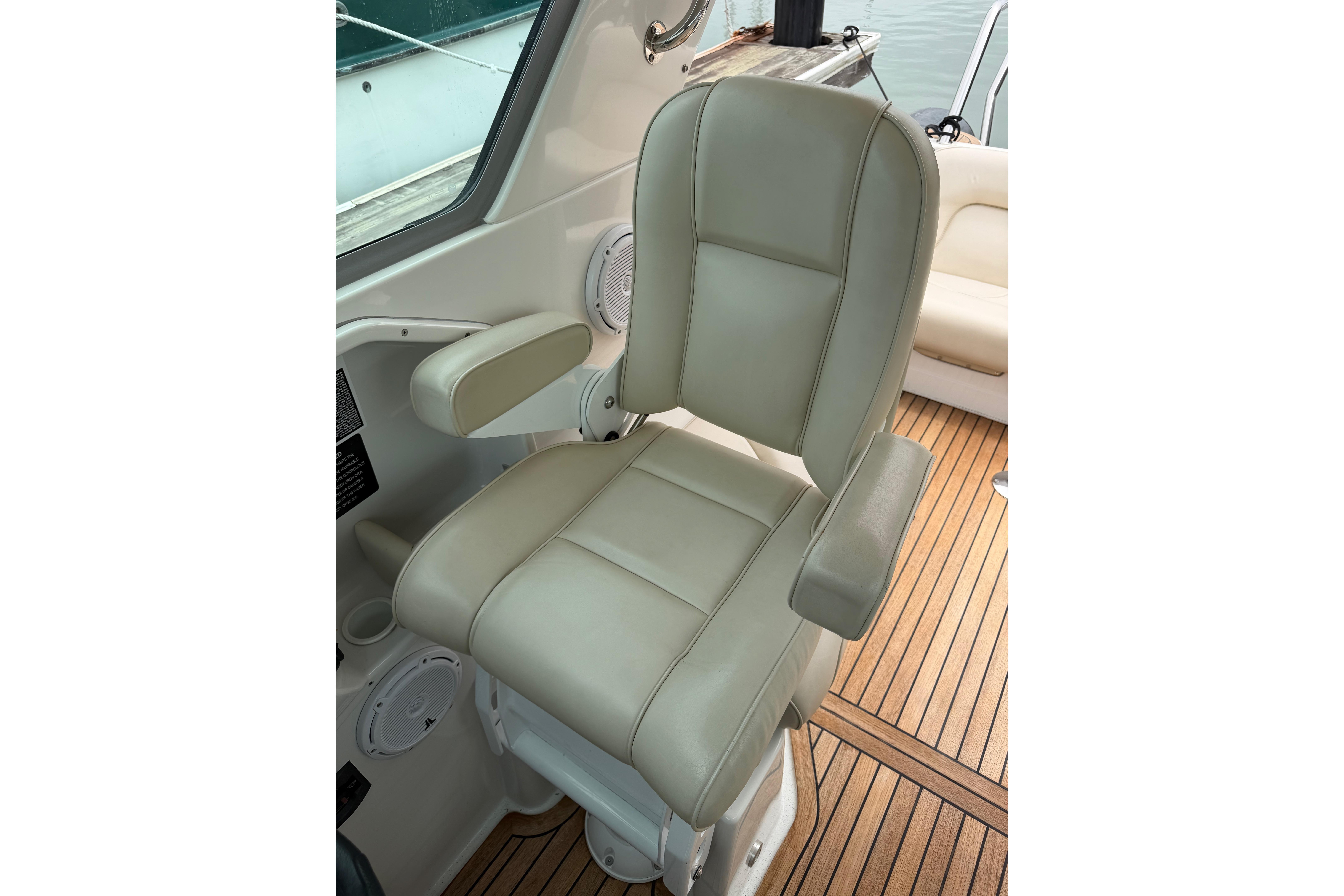 Captain's chair on 2016 Protector Targa 30 boat, featuring beige upholstery and armrests.