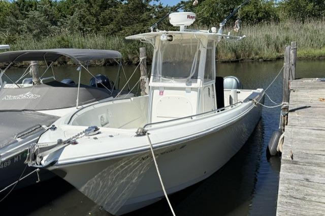 2006 Sailfish 2660 CC boat docked by a wooden pier in a serene setting.