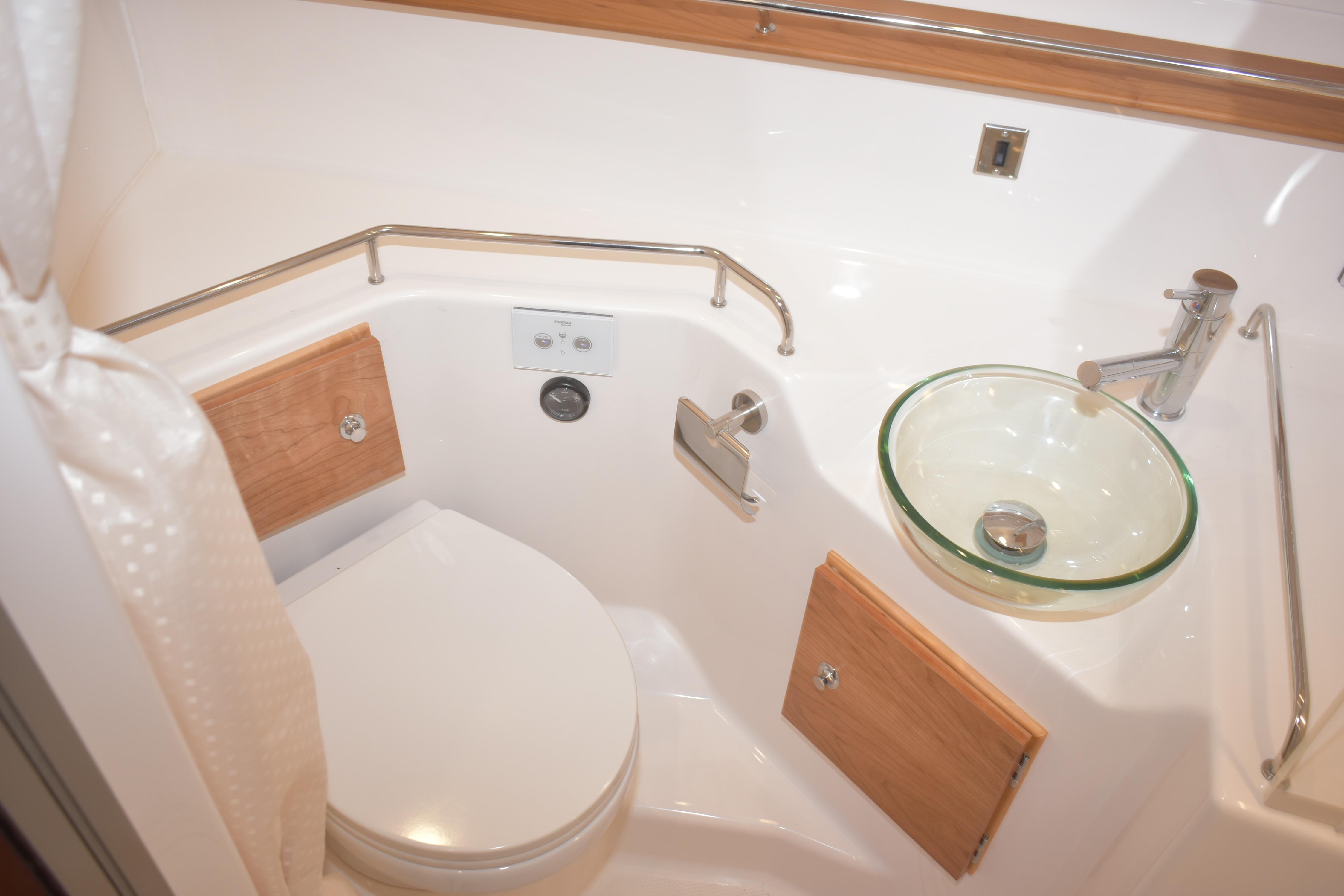 2026 Cutwater C-32 CB boat bathroom with modern glass sink and wooden accents.