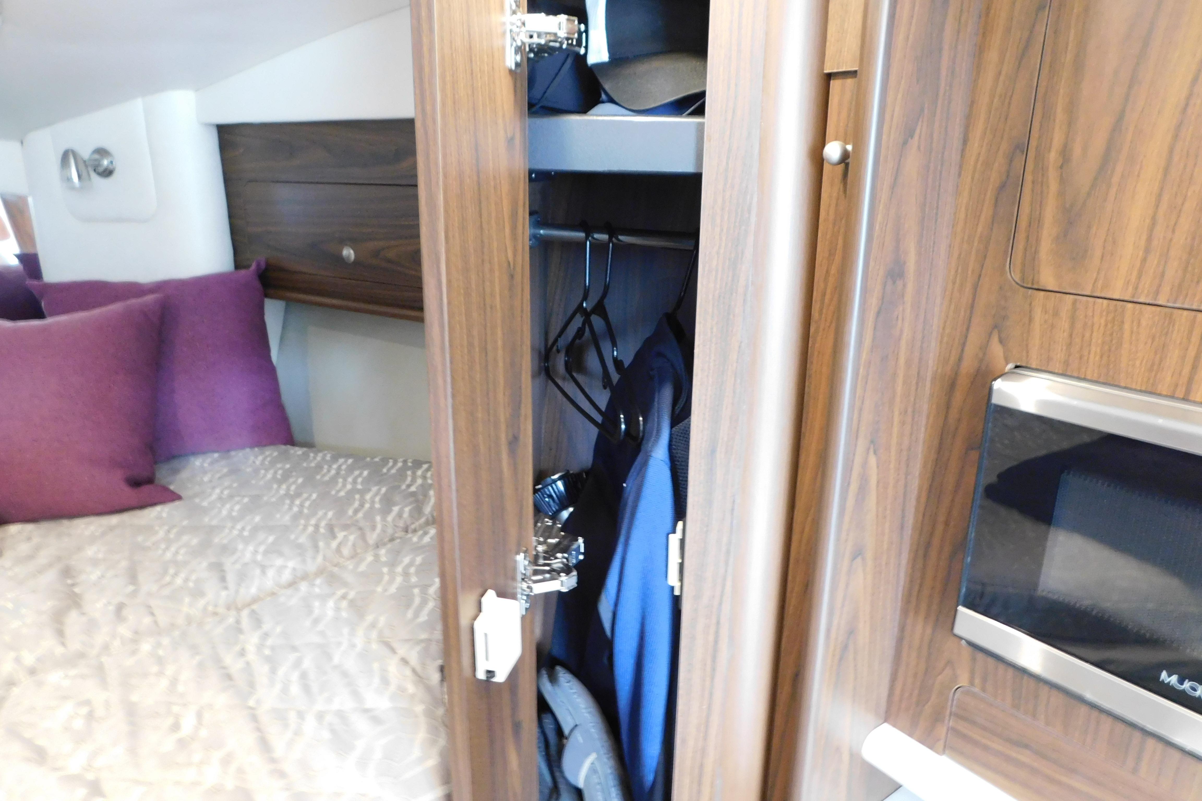 2017 Rinker EX 320 cabin interior with bed, closet, and microwave.