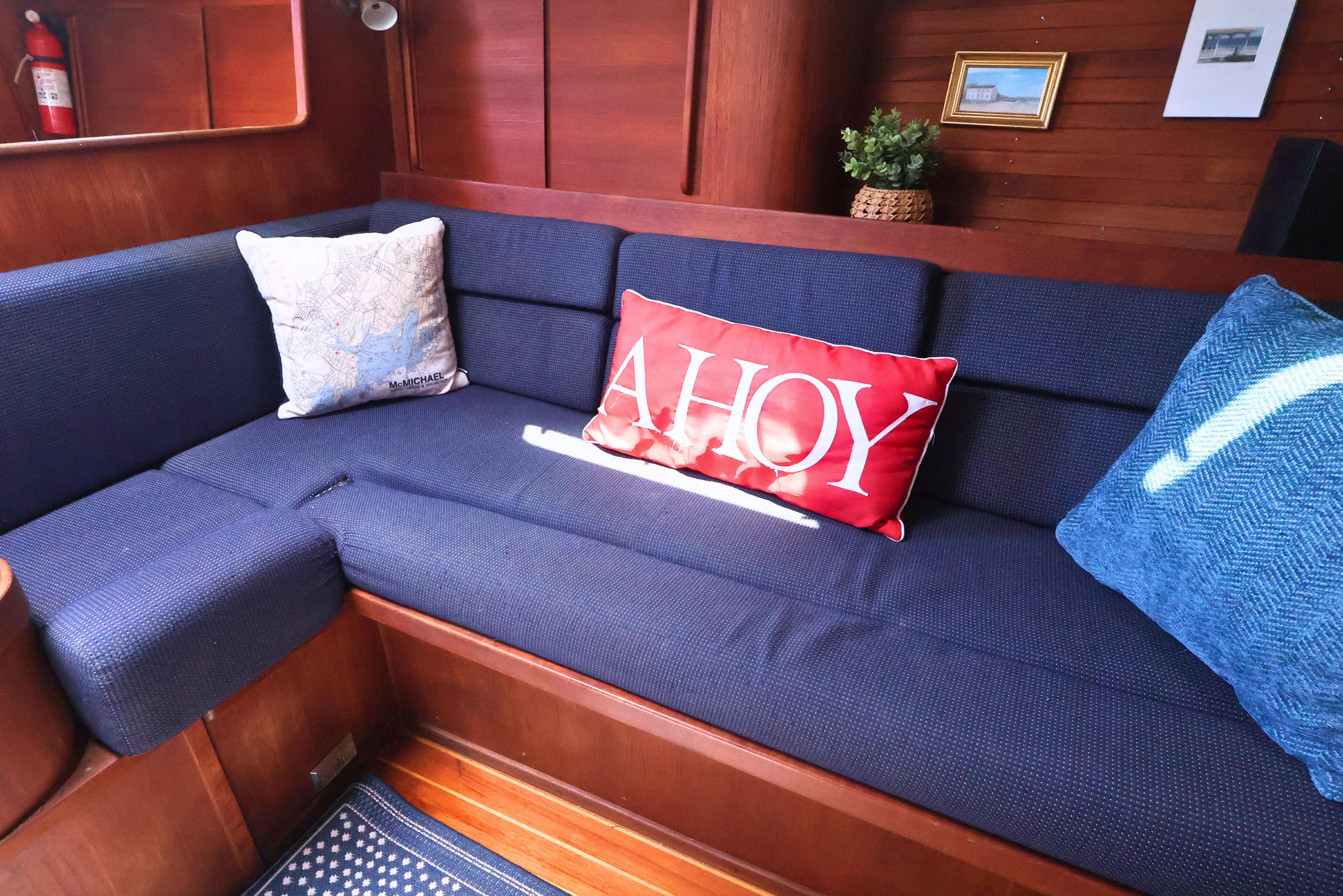 Cozy interior of 1989 J Boat J 40 with nautical-themed cushions and wooden paneling.