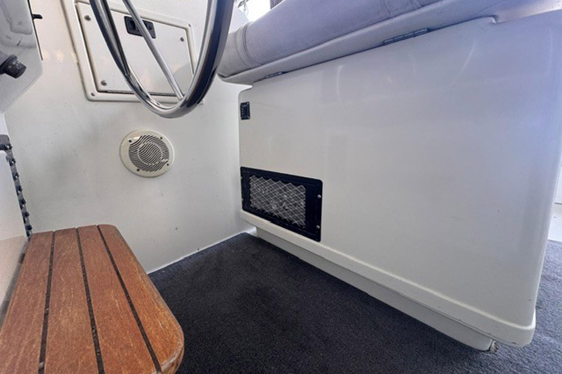 Interior of 1988 Tiara Yachts 3300 Open, featuring steering wheel and wooden bench.