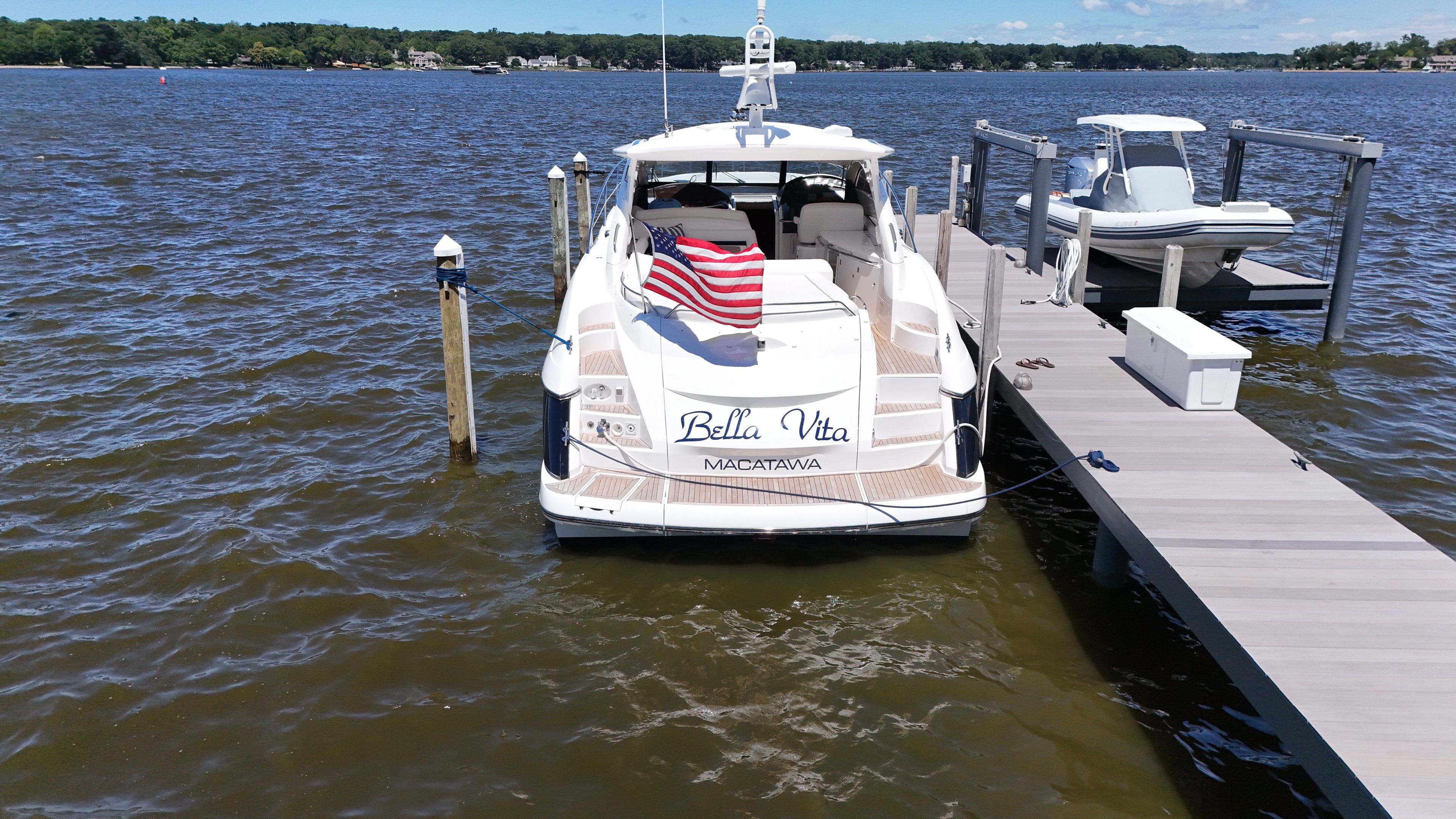A 2008 Sunseeker Portofino 53 docked at a pier. An American flag waves at the stern.