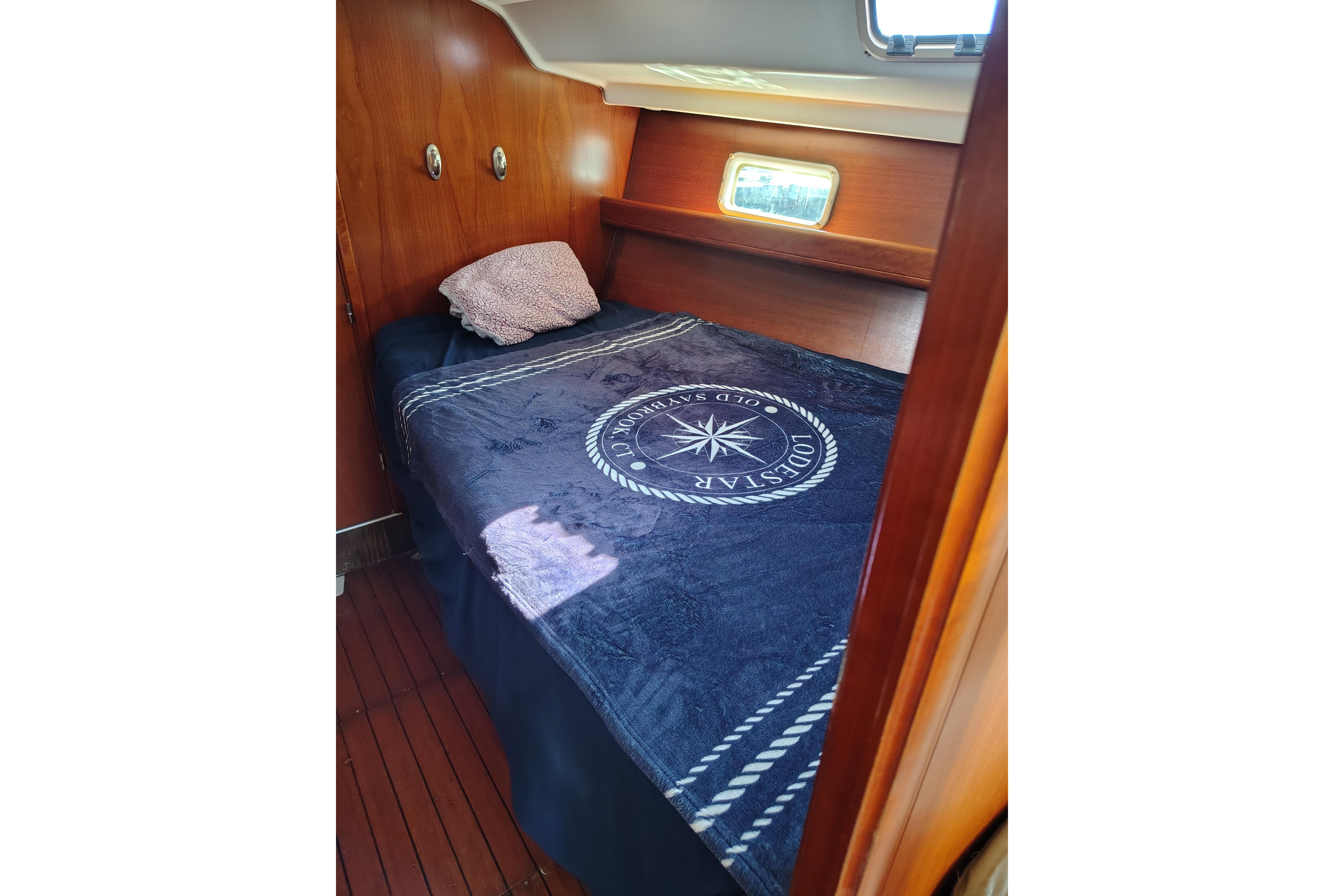 Cozy cabin interior of 2001 Beneteau Oceanis 411 sailboat with nautical-themed bedding.