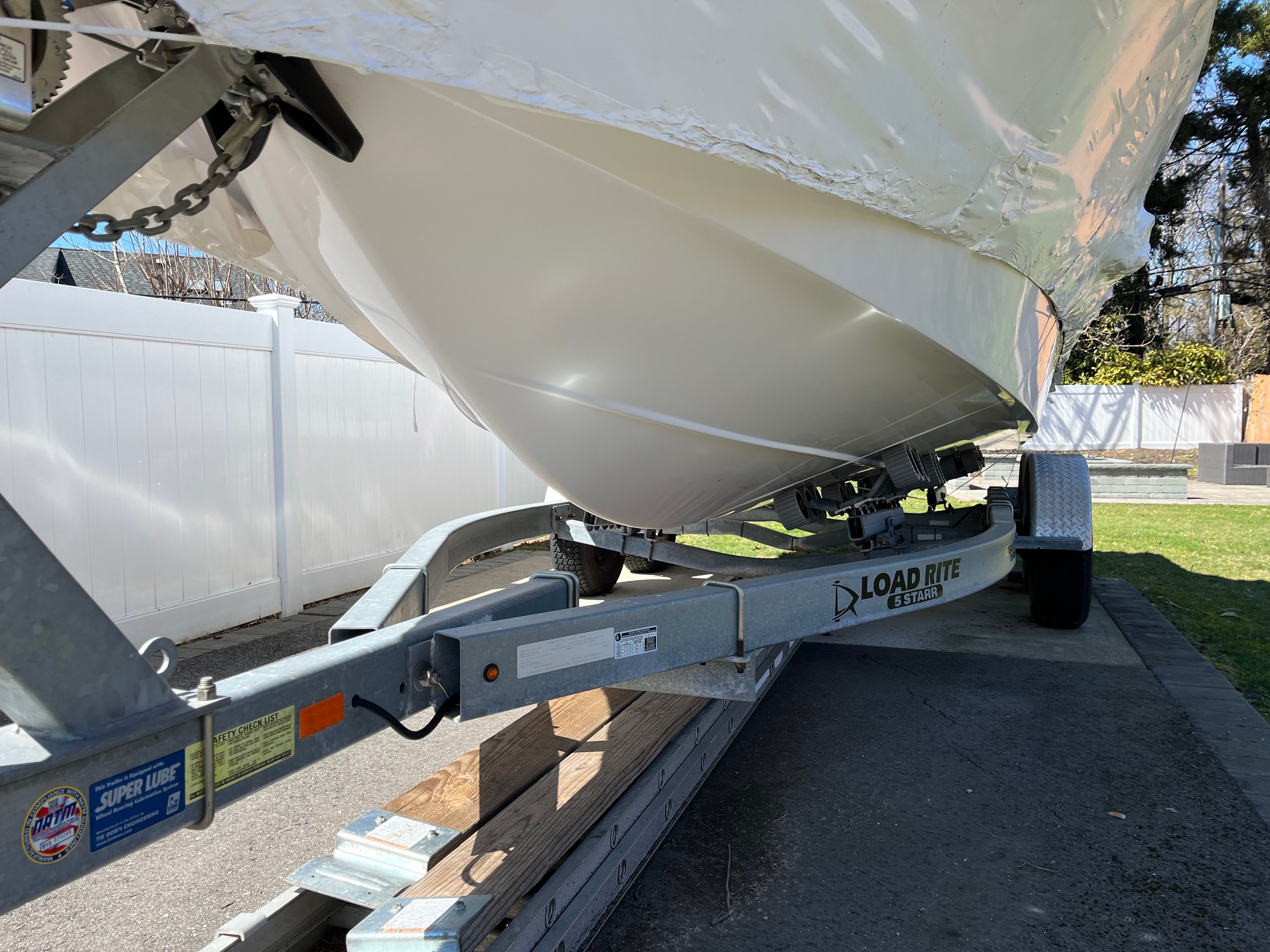 A 2002 Pro-Line Center Console boat on a trailer outdoors.