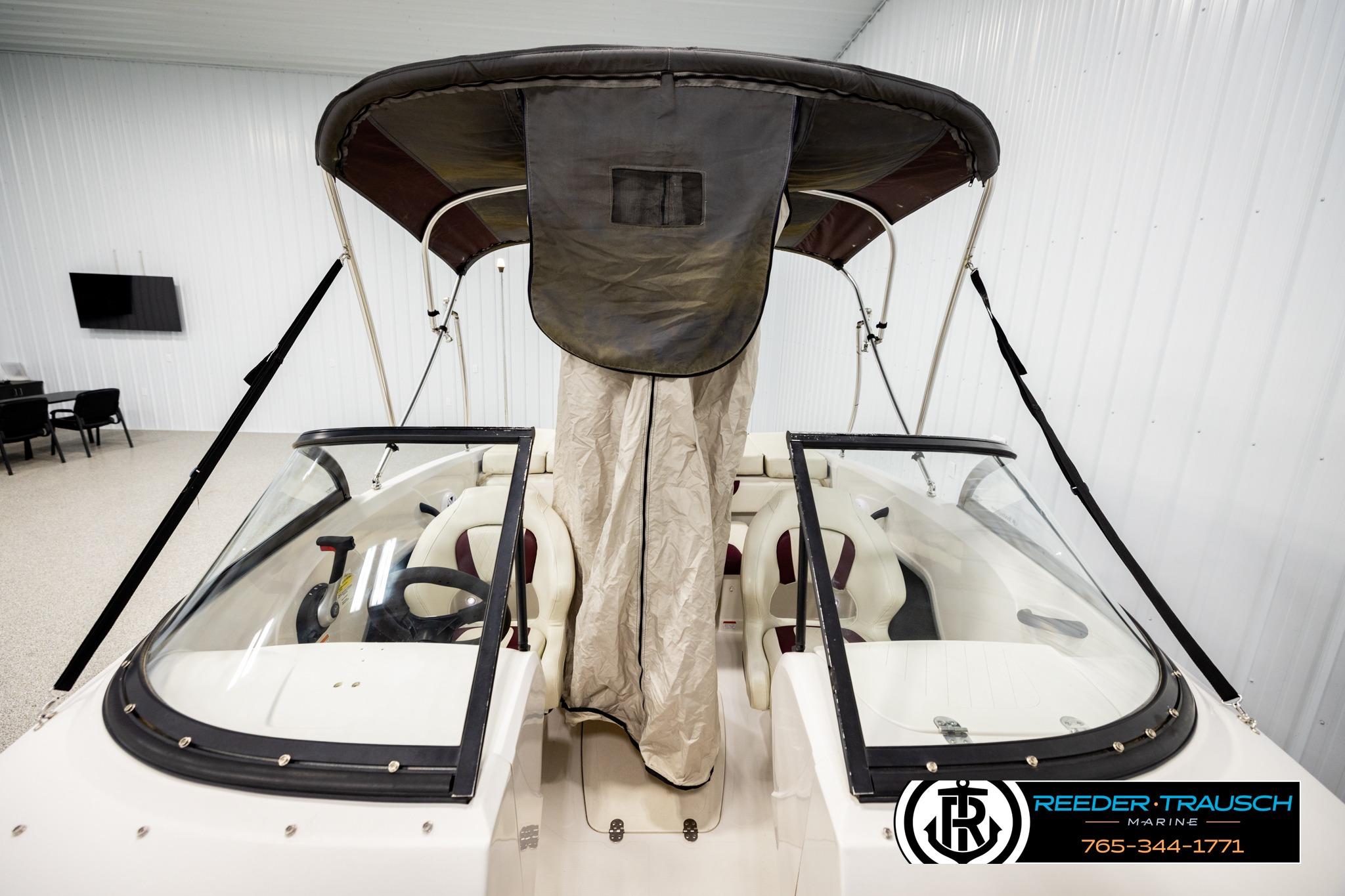 2016 Tahoe 450 TS boat with canopy in showroom, featuring dual seating and steering wheel.