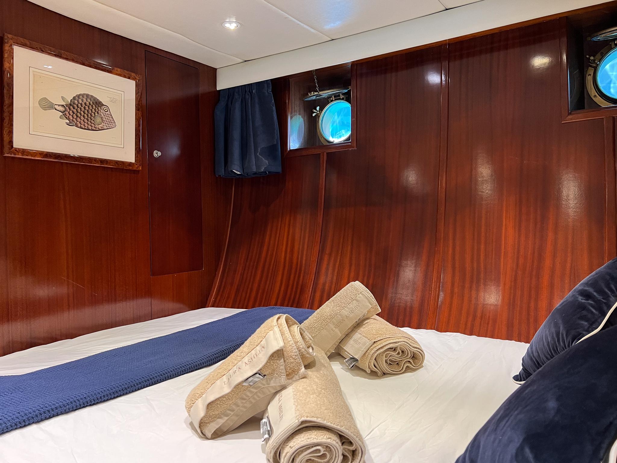 Luxurious wooden cabin interior of 1969 Psarros Shipyard yacht with bed and porthole.