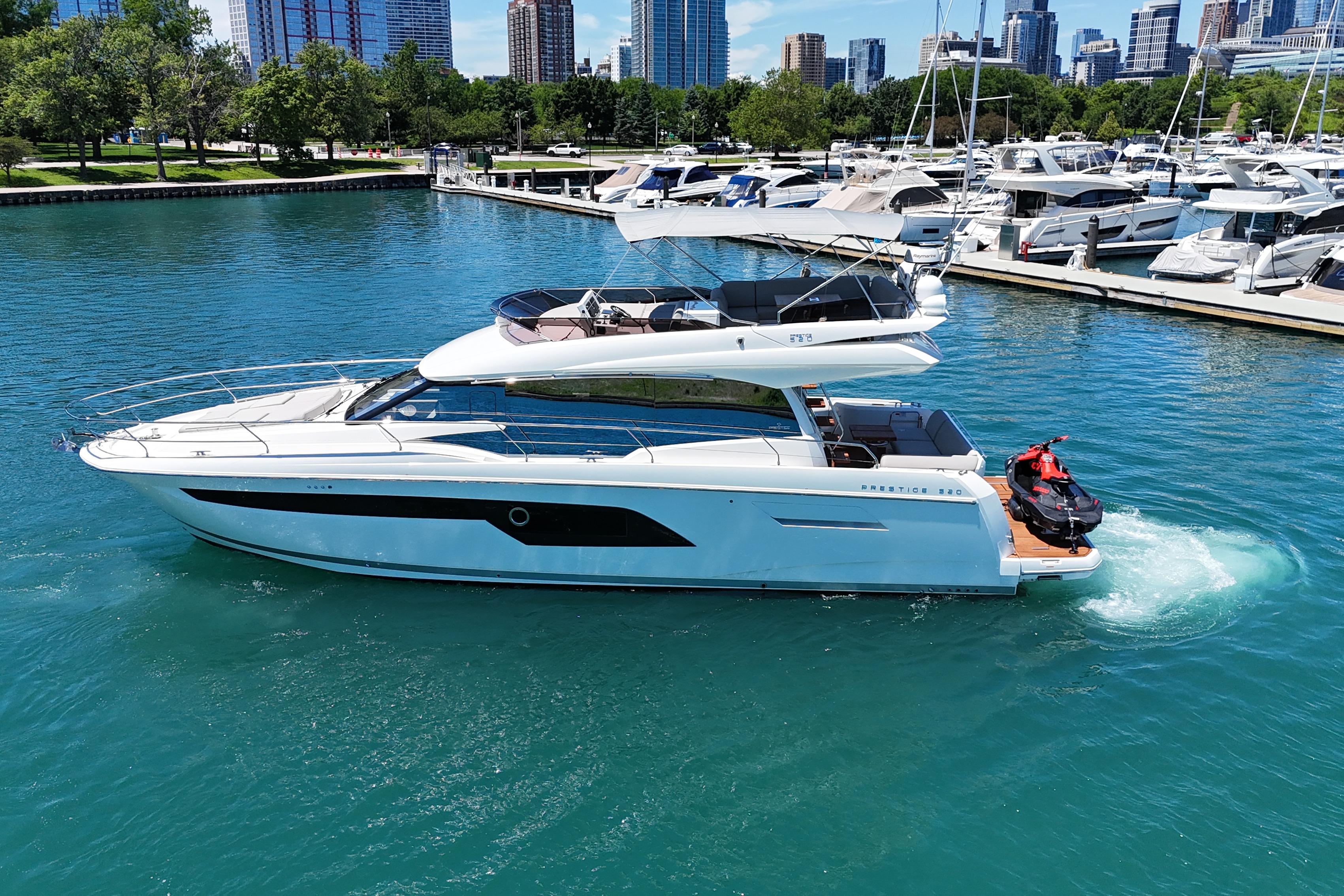 Luxury 2022 Prestige 520 yacht cruising in a marina with city skyline backdrop.