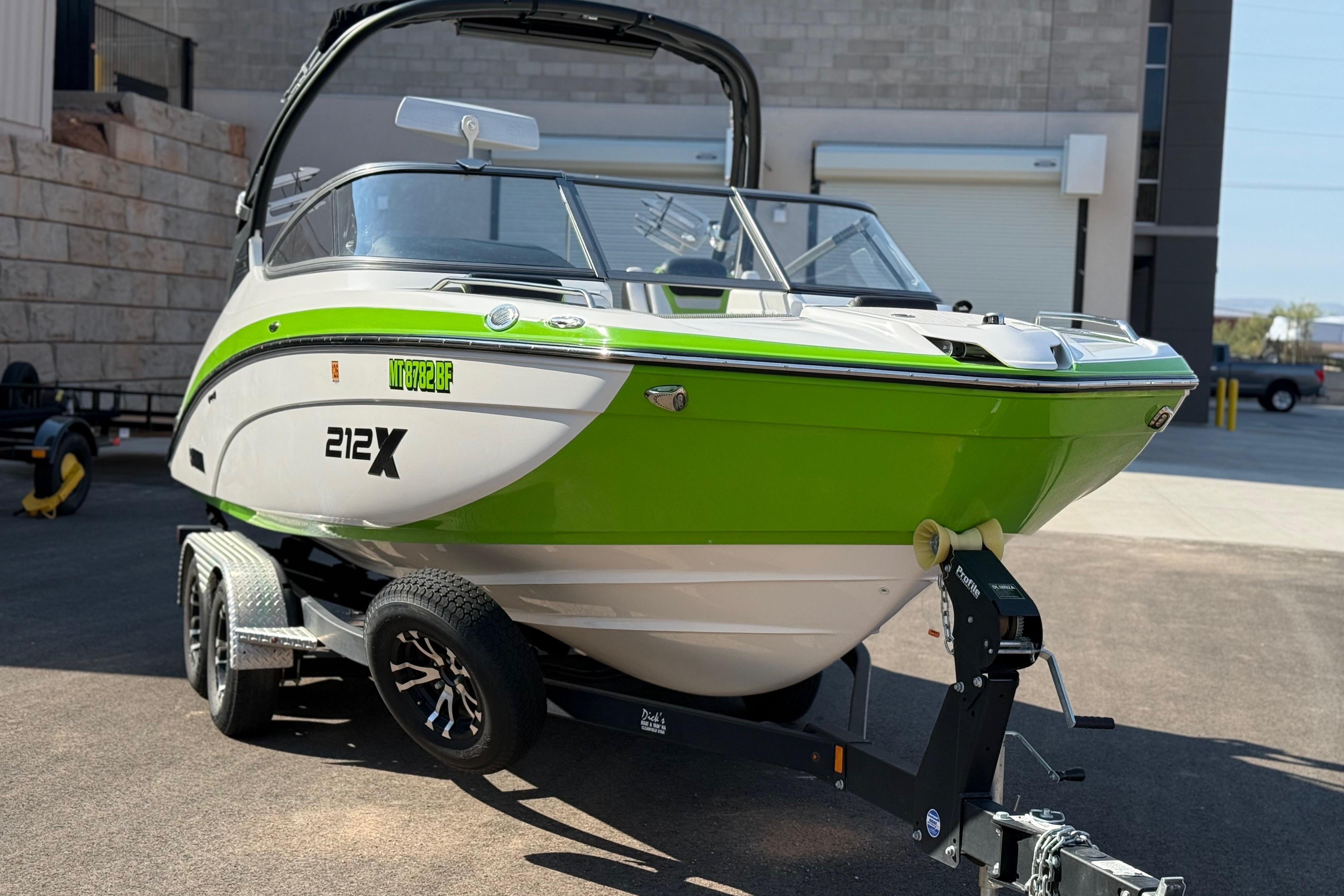 2022 Yamaha Boats 212XE in vibrant green on a trailer, parked outdoors.