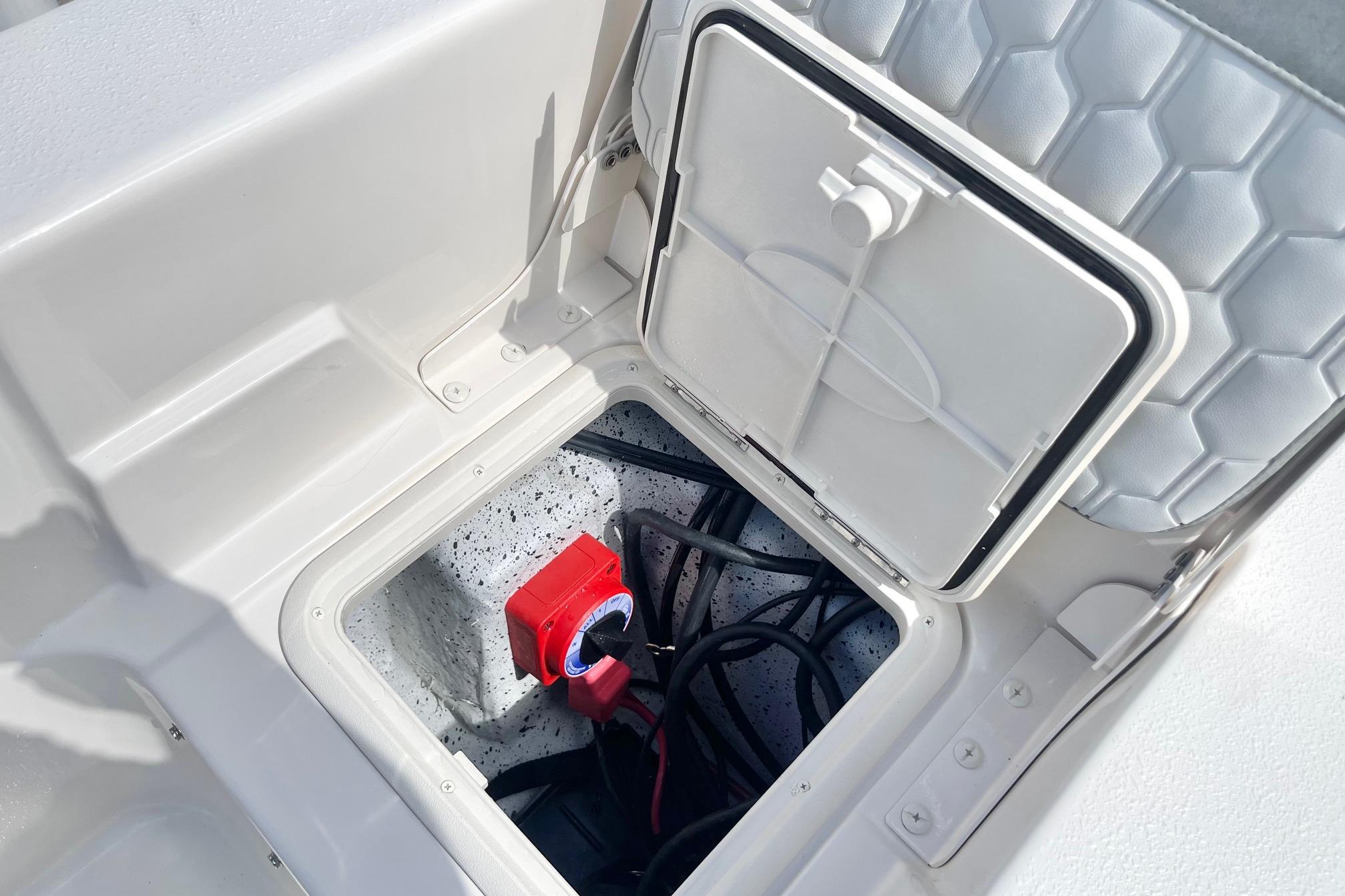2026 Carolina Skiff 19 LS boat storage compartment with wiring and red switch.