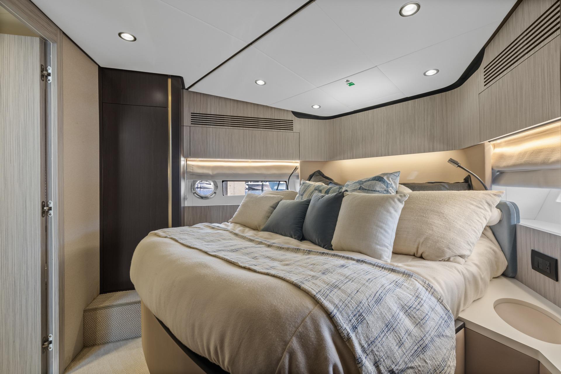 Luxurious bedroom interior of 2019 Azimut 55 yacht with modern design and cozy bedding.
