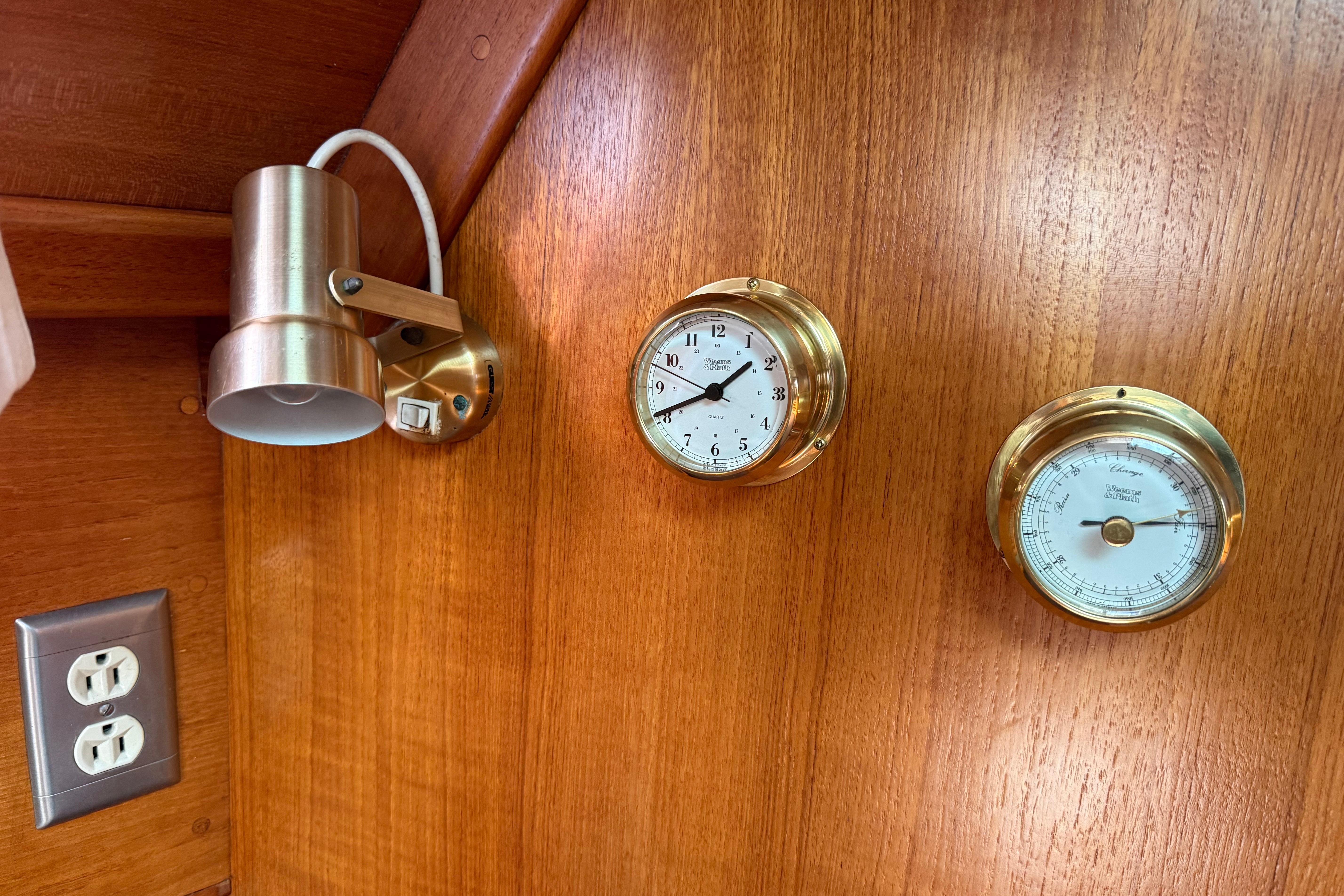 Brass clock and barometer on wooden panel in 1988 Ericson 32-200 sailboat interior.