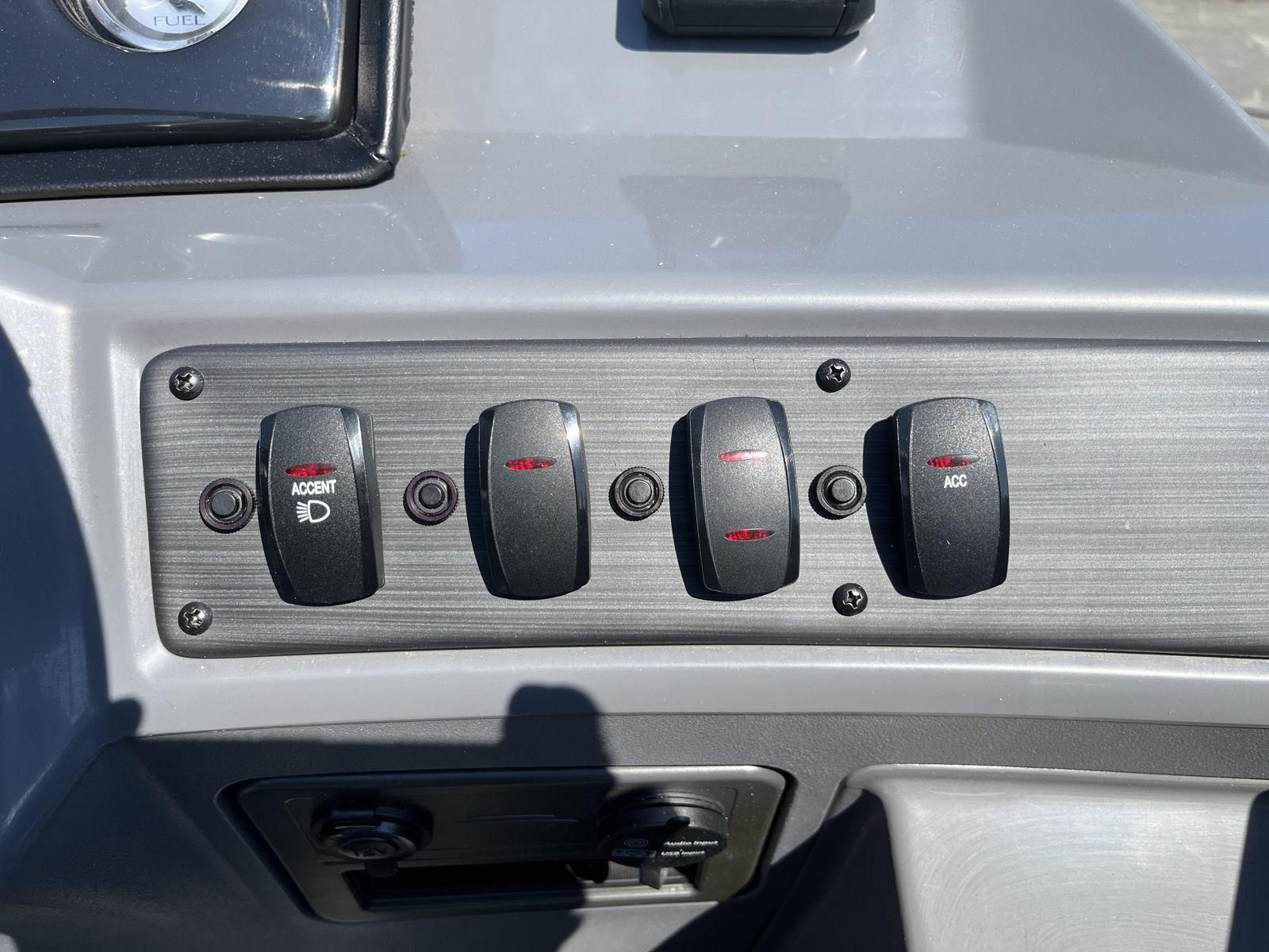 Close-up of a gray control panel area with several toggle switches and a dial.