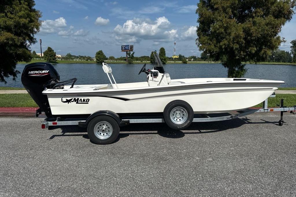 2026 Mako Pro Skiff 17 CC boat on trailer by a lake, sunny day.