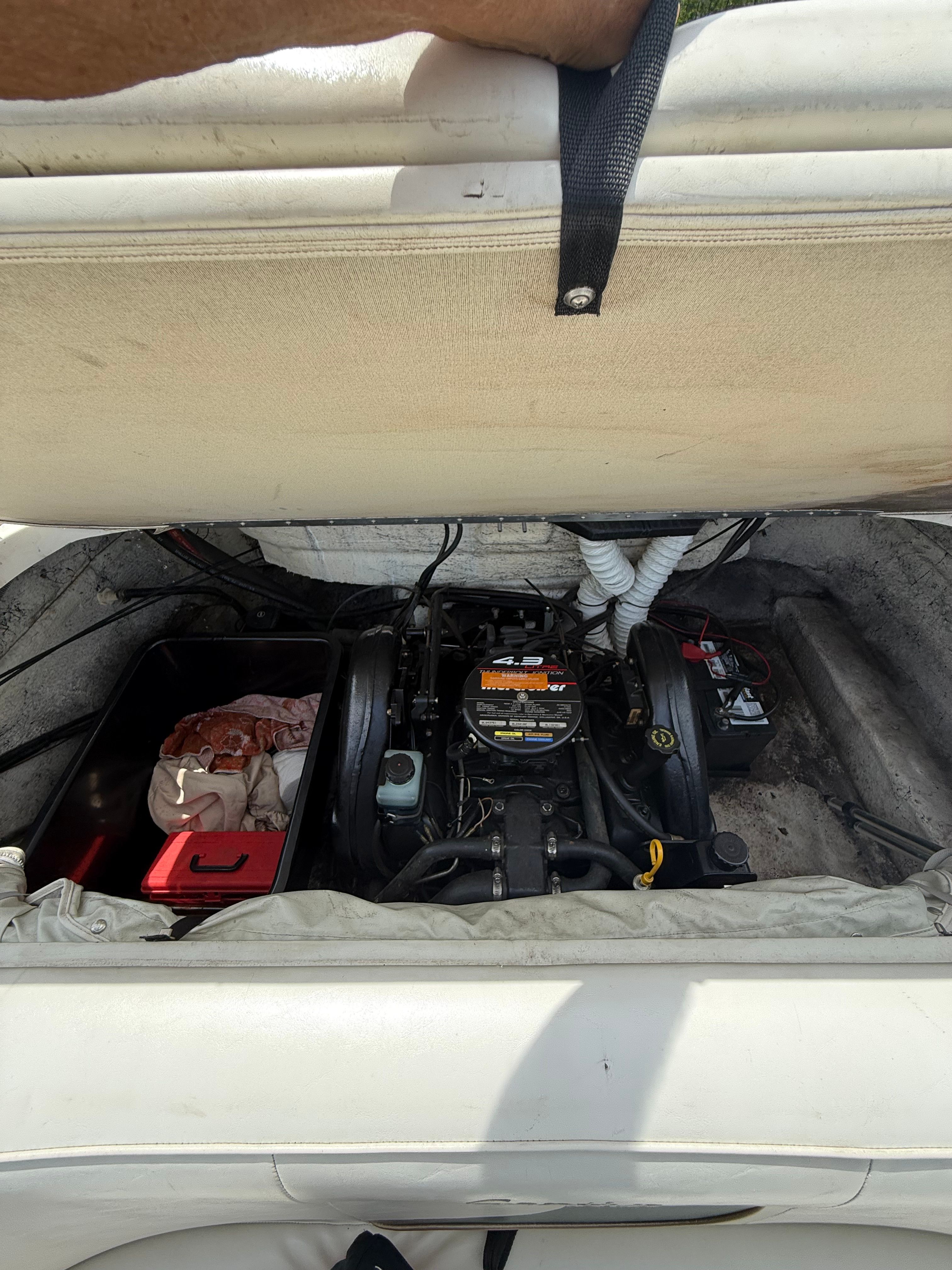 An open engine compartment of a boat with visible engine and batteries.