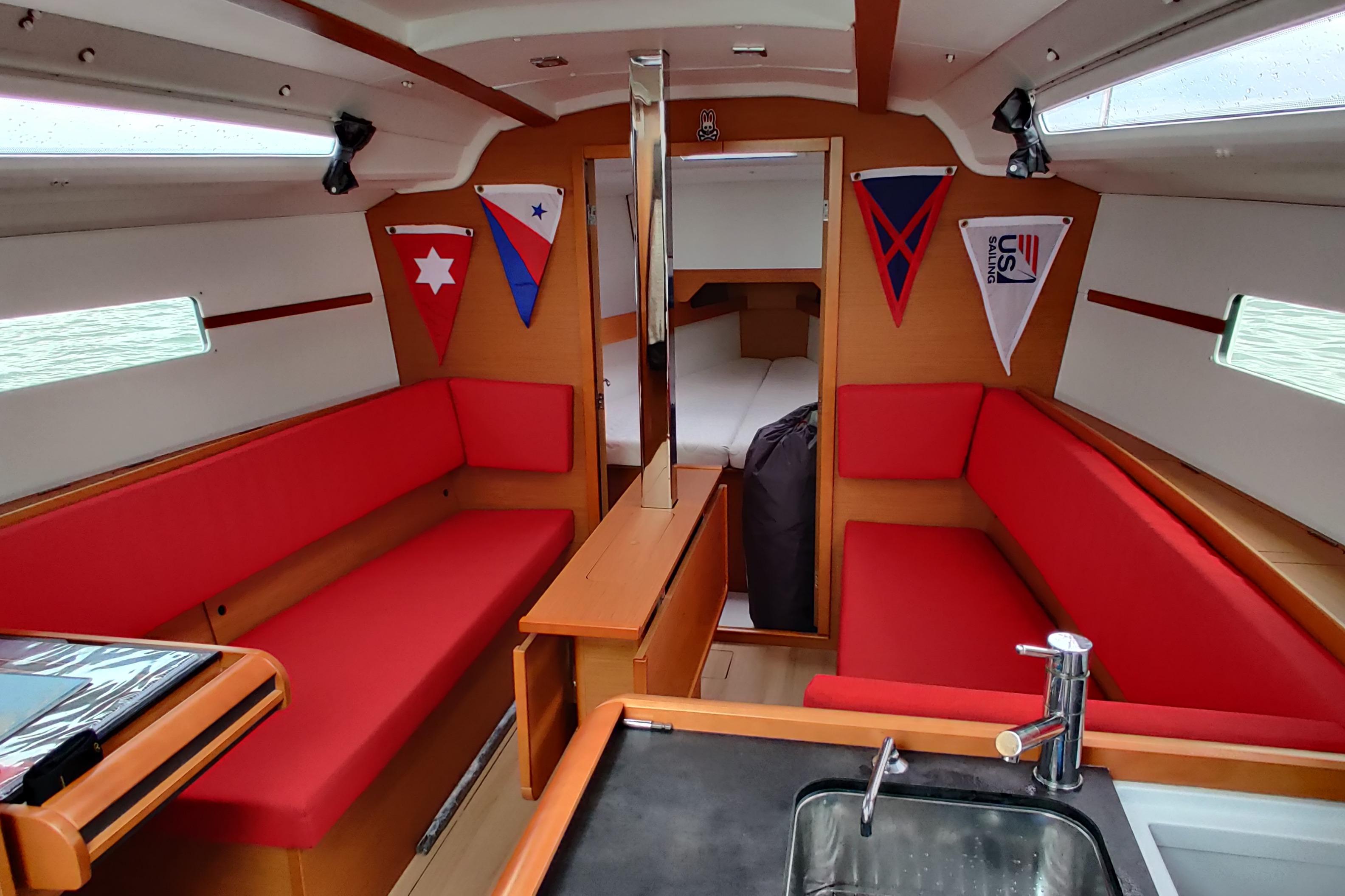 Interior of 2016 Jeanneau Sun Odyssey 349 sailboat with red seating and nautical decor.