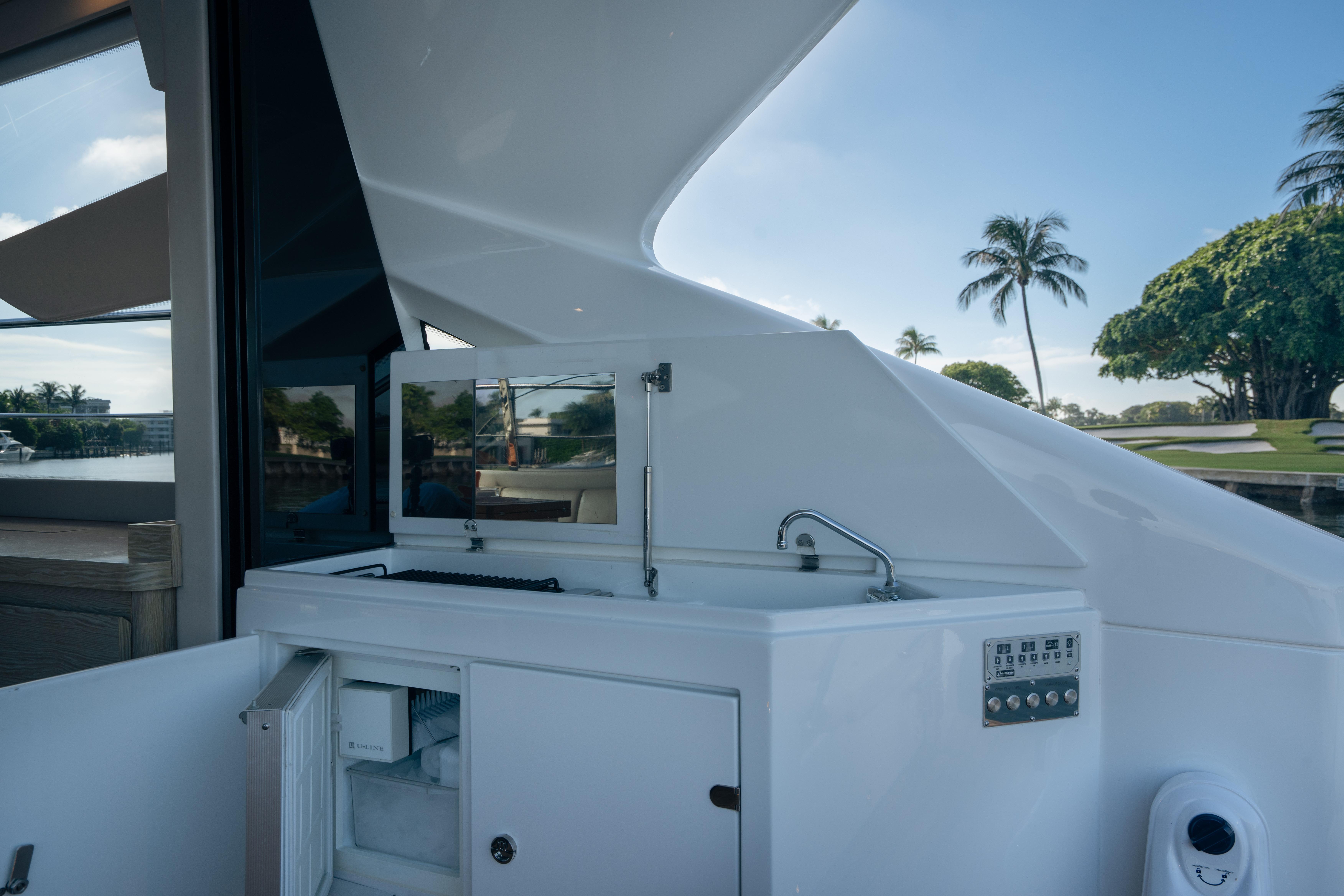 Outdoor kitchenette on 2019 Filippetti S55 yacht with sink and storage, surrounded by scenic views.