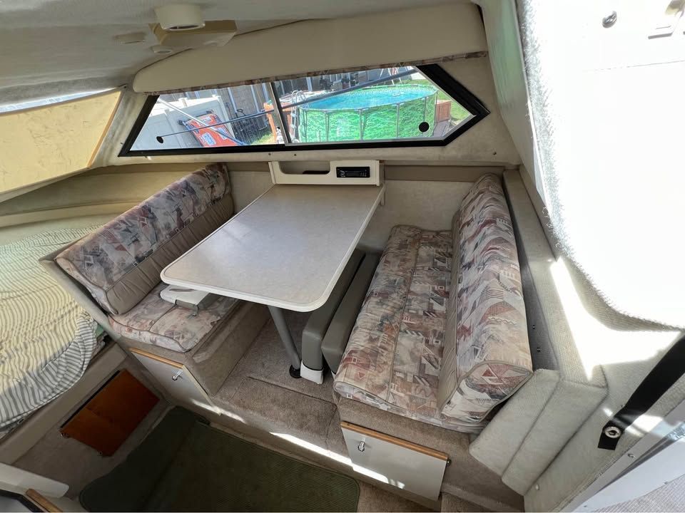 Interior of a 1999 Bayliner 2452 with dining table and benches.