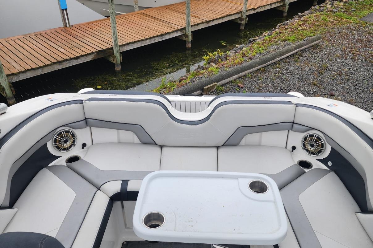 2015 Yamaha Boats 212X interior with seating, table, and speakers near dock.