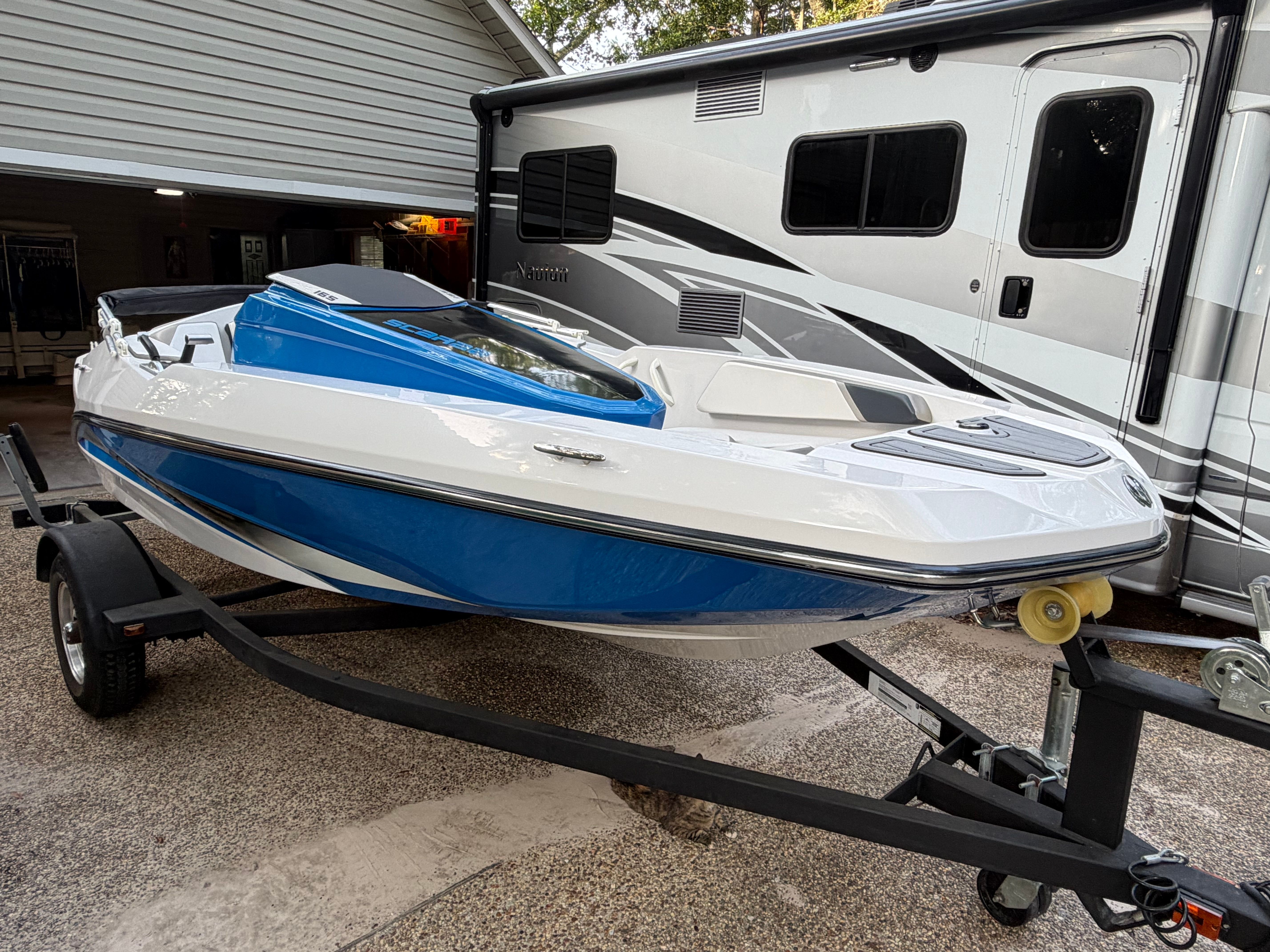 A 2015 Scarab 165 boat on a trailer next to an RV.