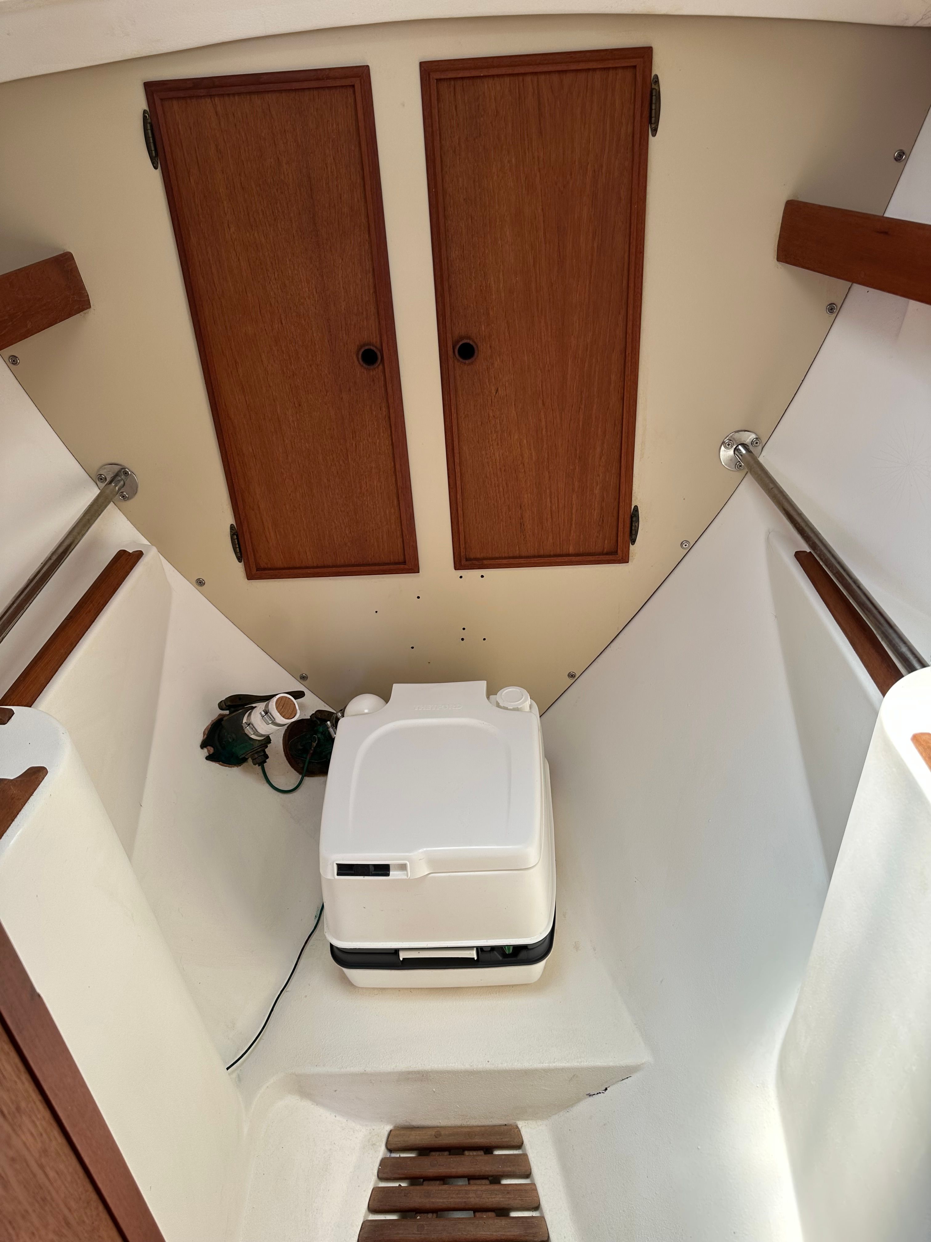 Interior of a 1985 Cape Dory 25D with a portable toilet and wooden cabinets.