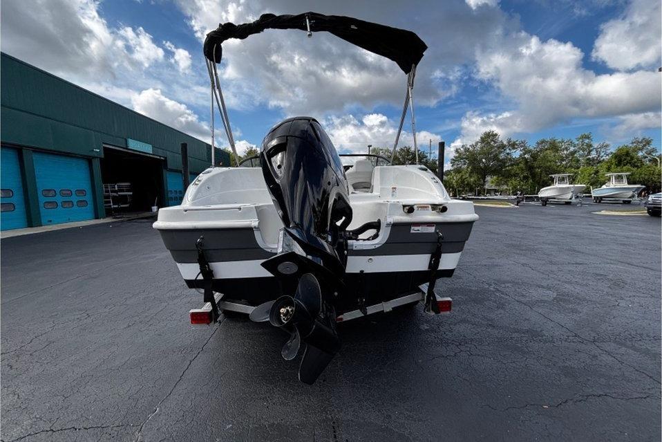 2022 Hurricane SunDeck 217 OB boat with outboard motor, parked outdoors under a cloudy sky.