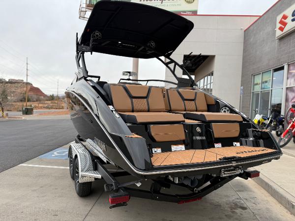 2025 Yamaha Boats 255XD, sleek black design, parked on trailer outside dealership.