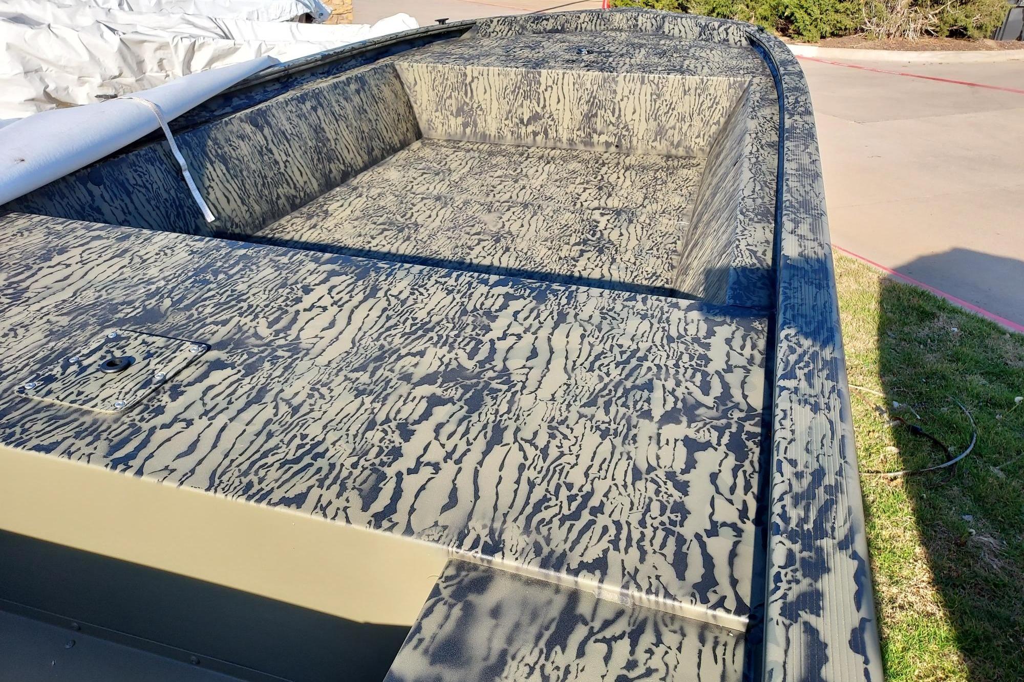 2026 Tracker Grizzly 1648 Utility boat with camouflage pattern, parked outdoors.