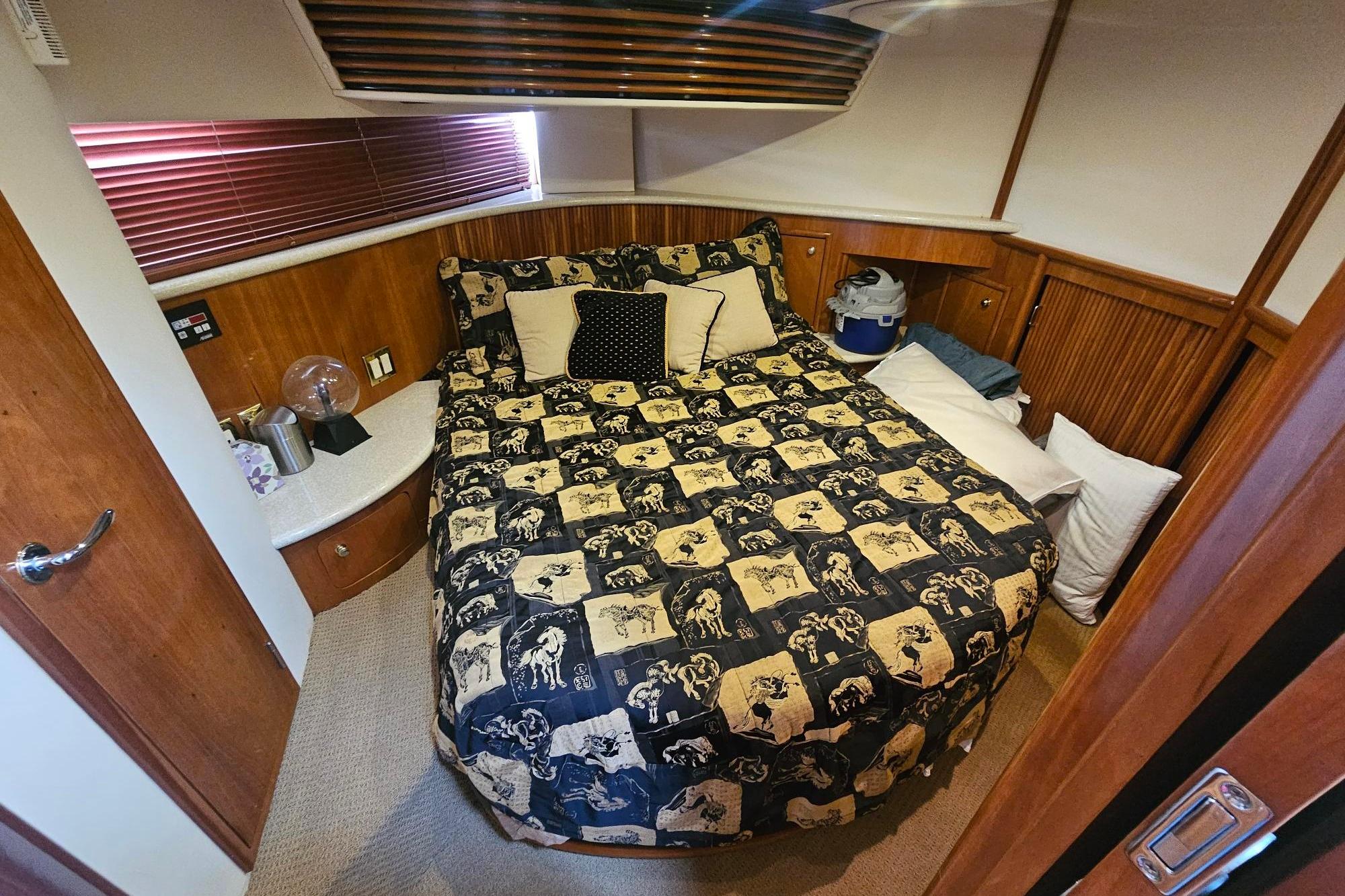 Cozy bedroom in 2002 Carver 450 Voyager Pilothouse with patterned bedding and wooden accents.