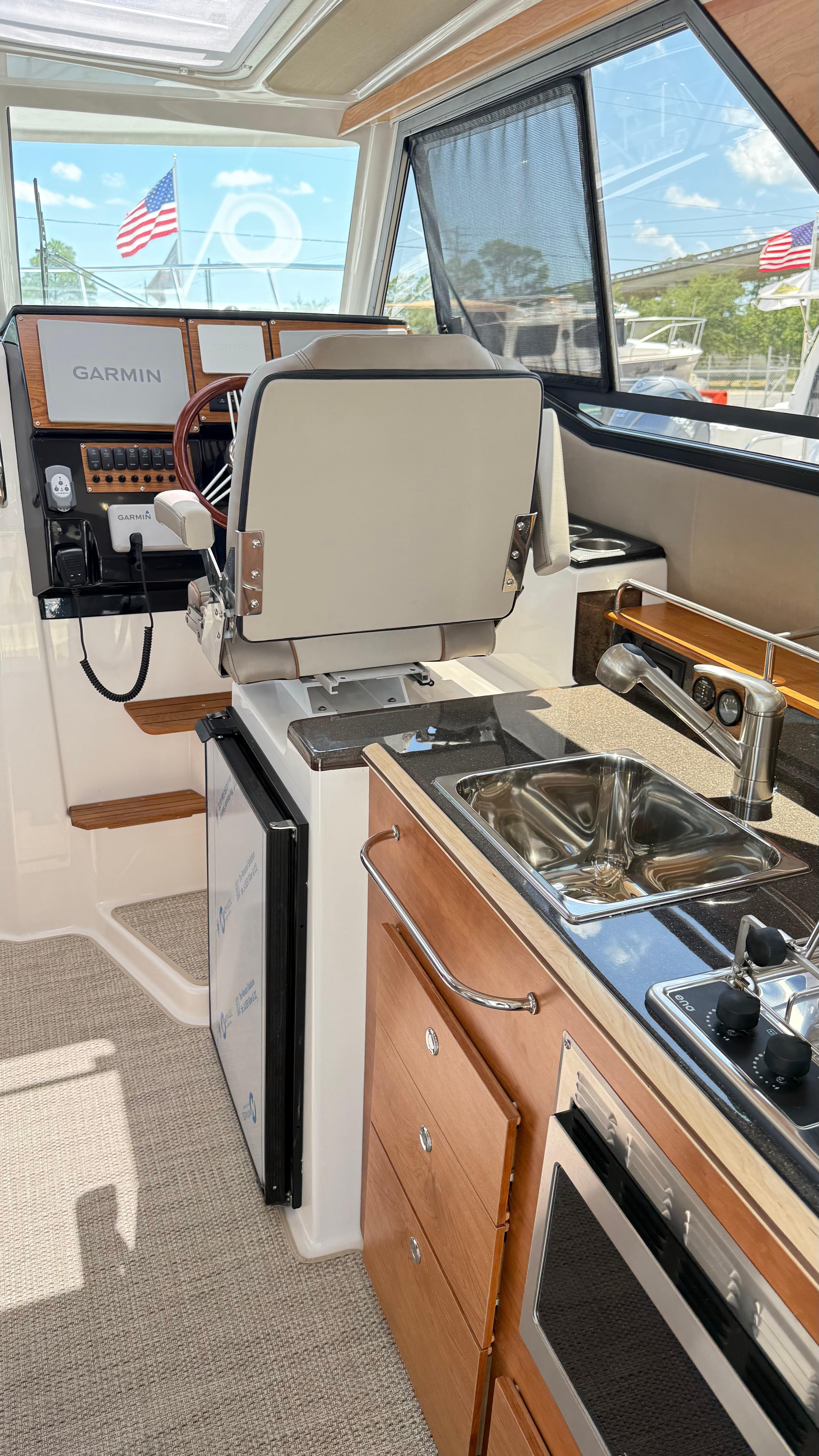 Interior of 2026 Cutwater C-288 Coupe featuring helm, kitchen sink, and appliances.