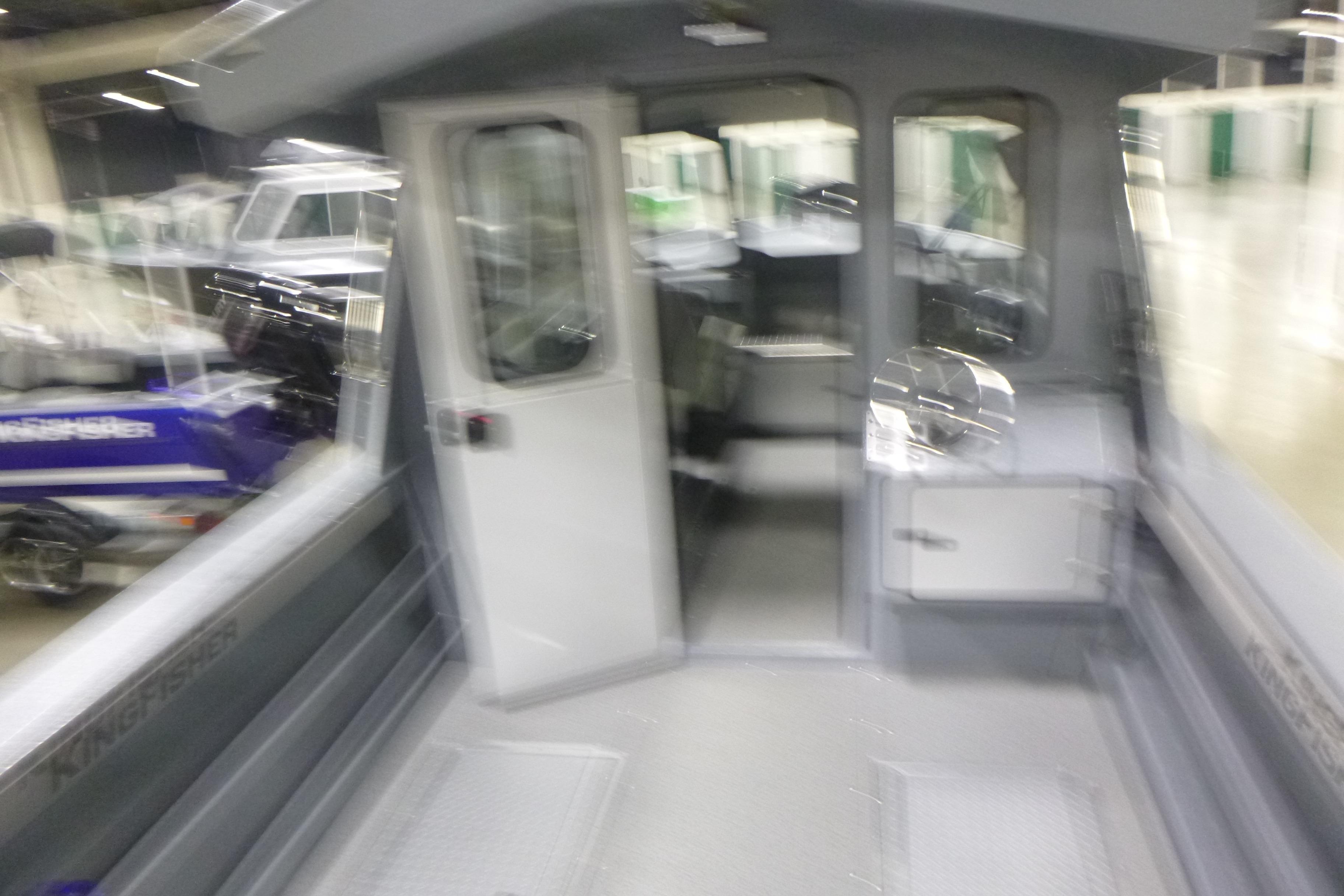 Blurry interior view of a 2026 KingFisher 2425 Escape HT boat at a showroom.