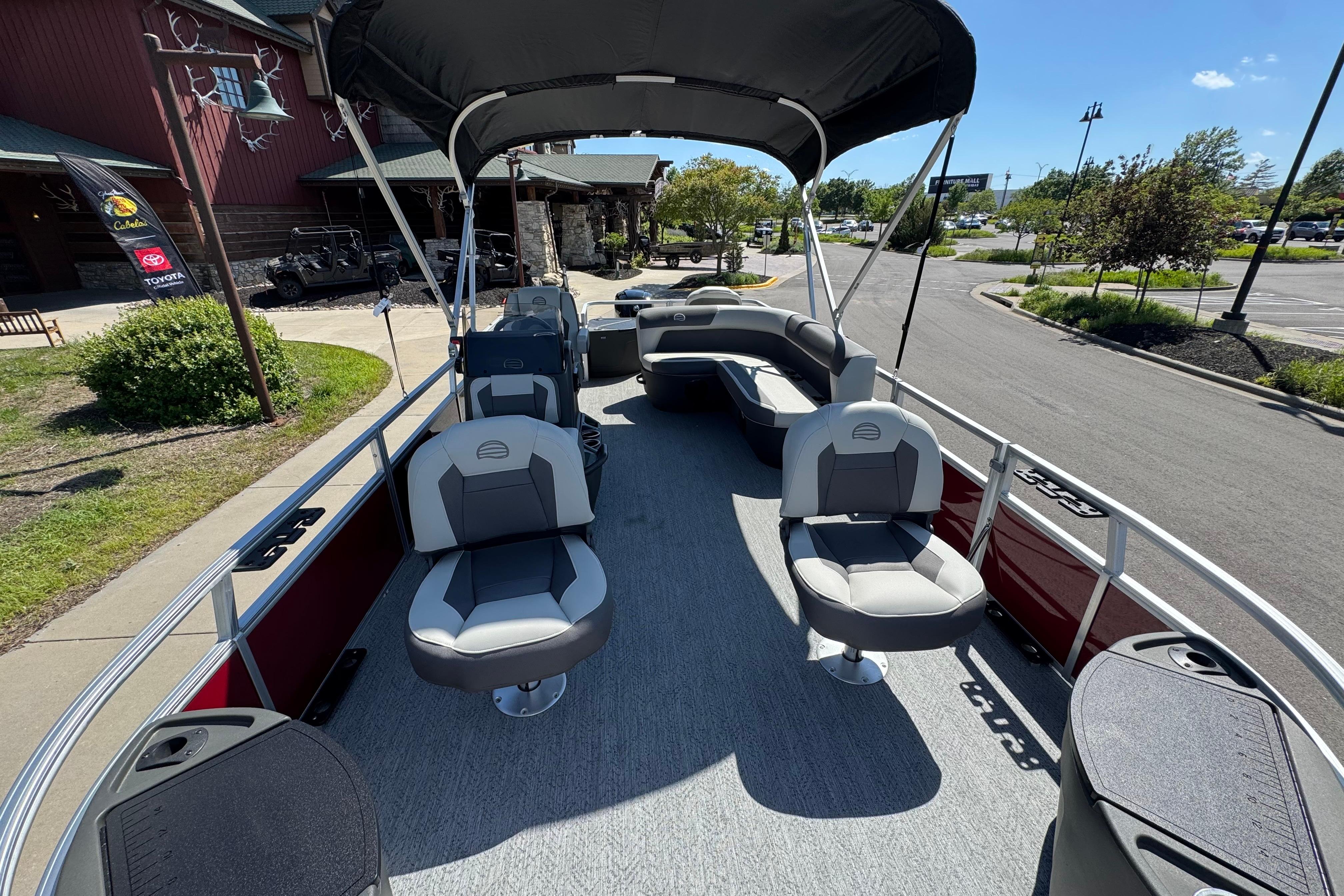 2026 Sun Tracker Bass Buggy 18 DLX pontoon boat with seating and canopy in a parking lot.