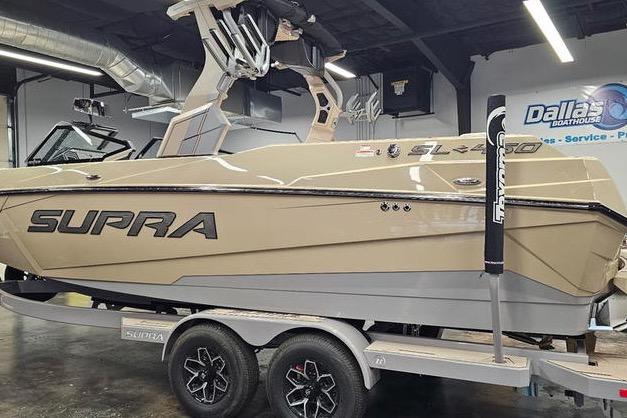 2026 Supra SL boat on trailer in showroom, featuring sleek design and modern features.