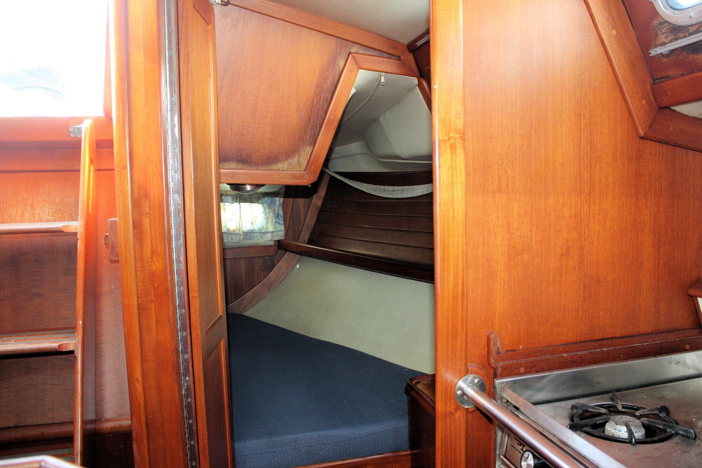 Interior of 1987 Ericson 38-200 sailboat with wooden cabinetry and cozy sleeping area.