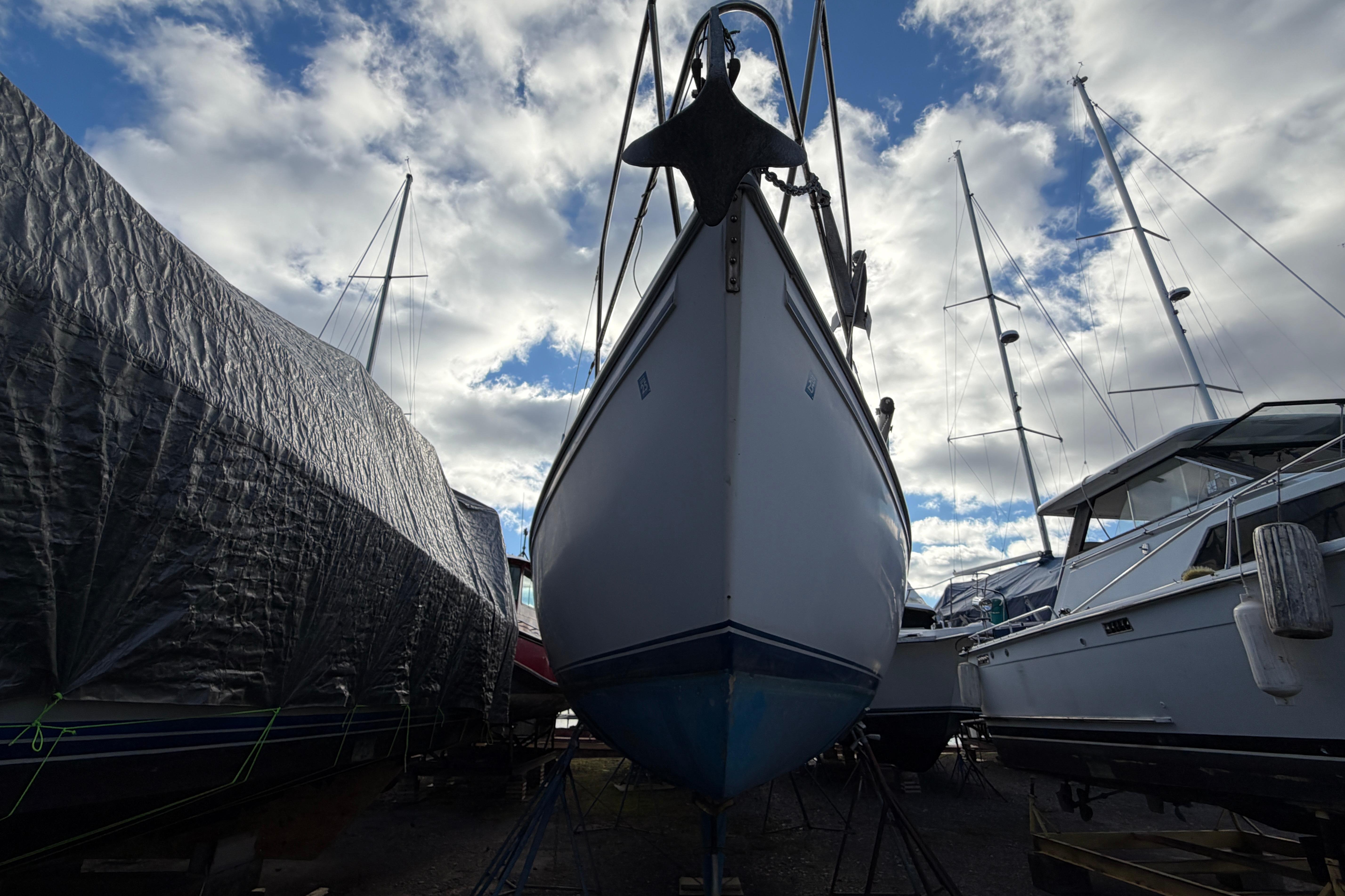 1985 Catalina 36 sailboat in dry dock, surrounded by other boats under a cloudy sky.
