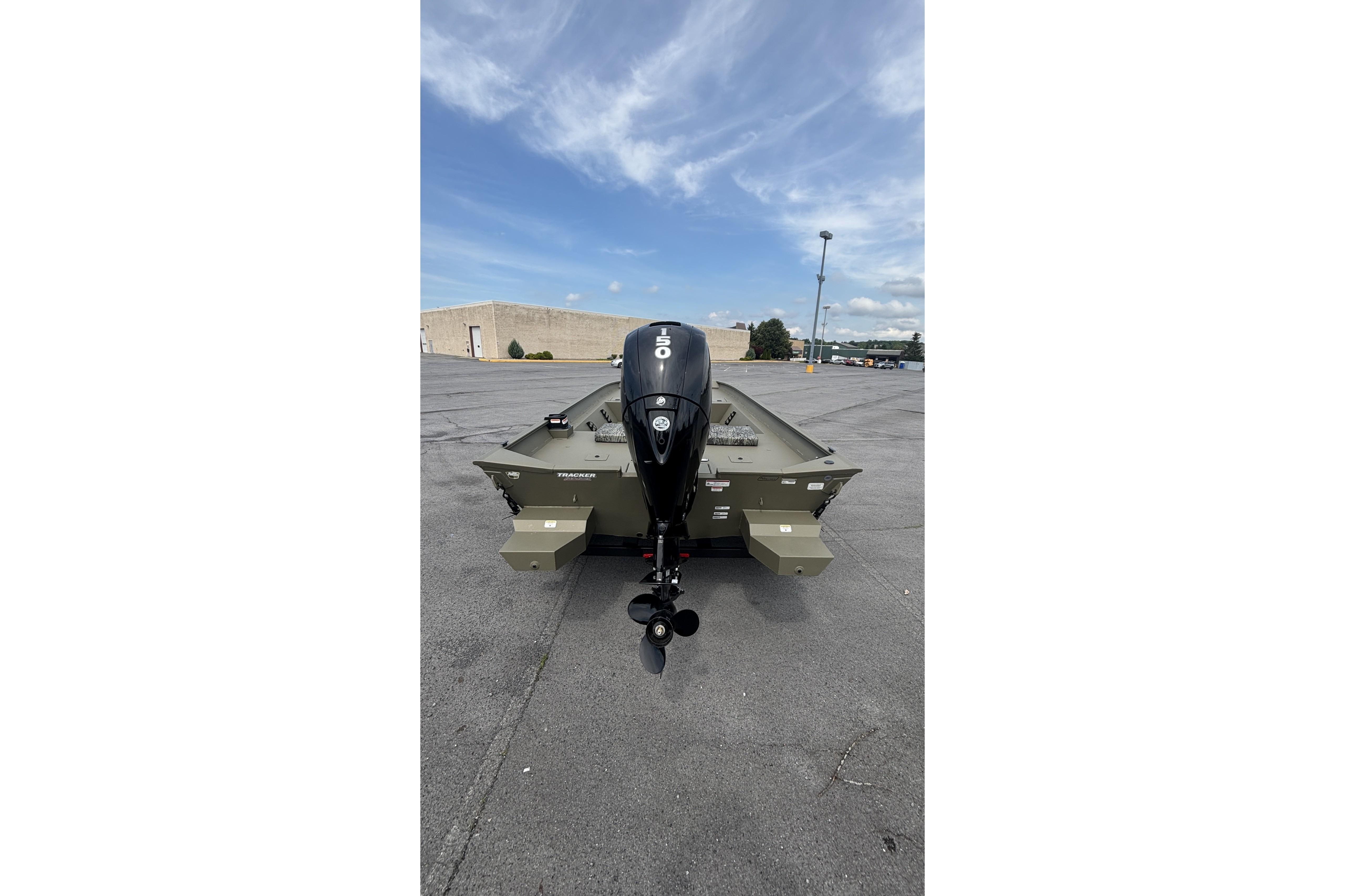 2026 Tracker Grizzly 2072 CC boat with outboard motor in parking lot.