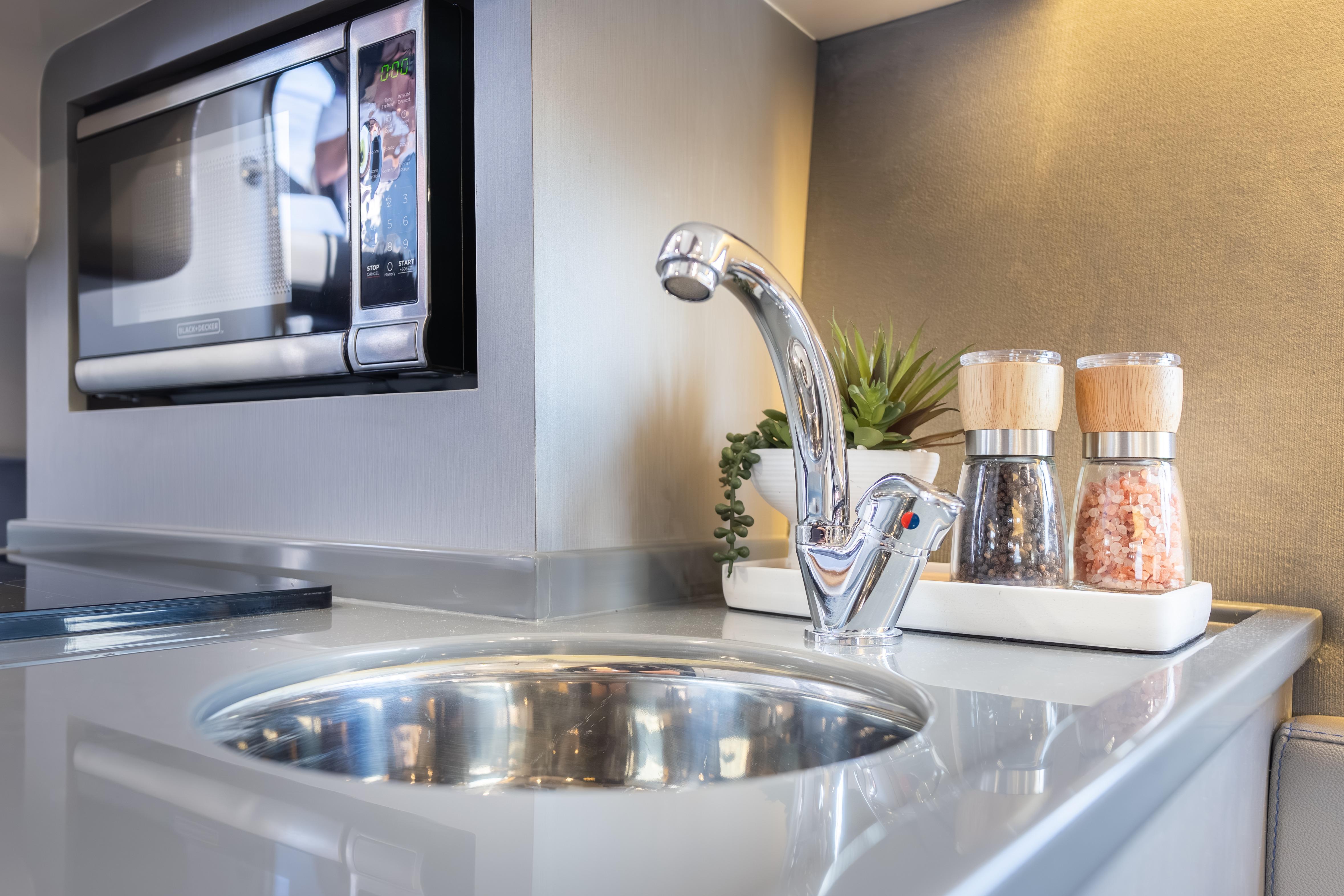 Modern kitchen in Hanover 347, 2026 model, featuring sink, microwave, and spice set.