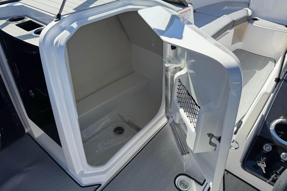2026 Yamaha Boats AR250 interior storage compartment with open door and cup holders.