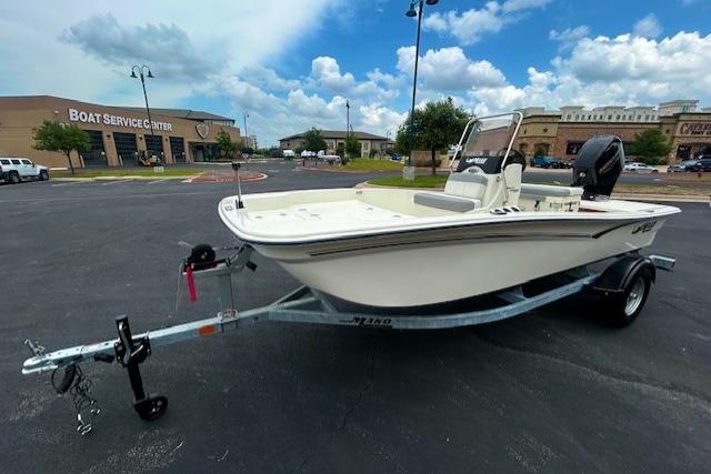 2026 Mako Pro Skiff 15 CC boat on trailer in parking lot, cloudy sky background.