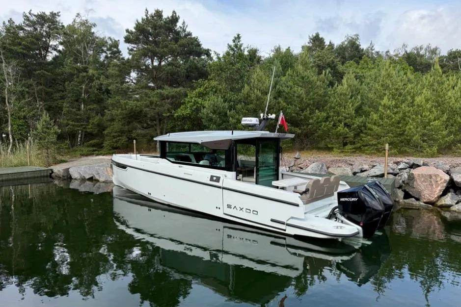 2022 Saxdor 320 GTC boat docked in a serene forested area.