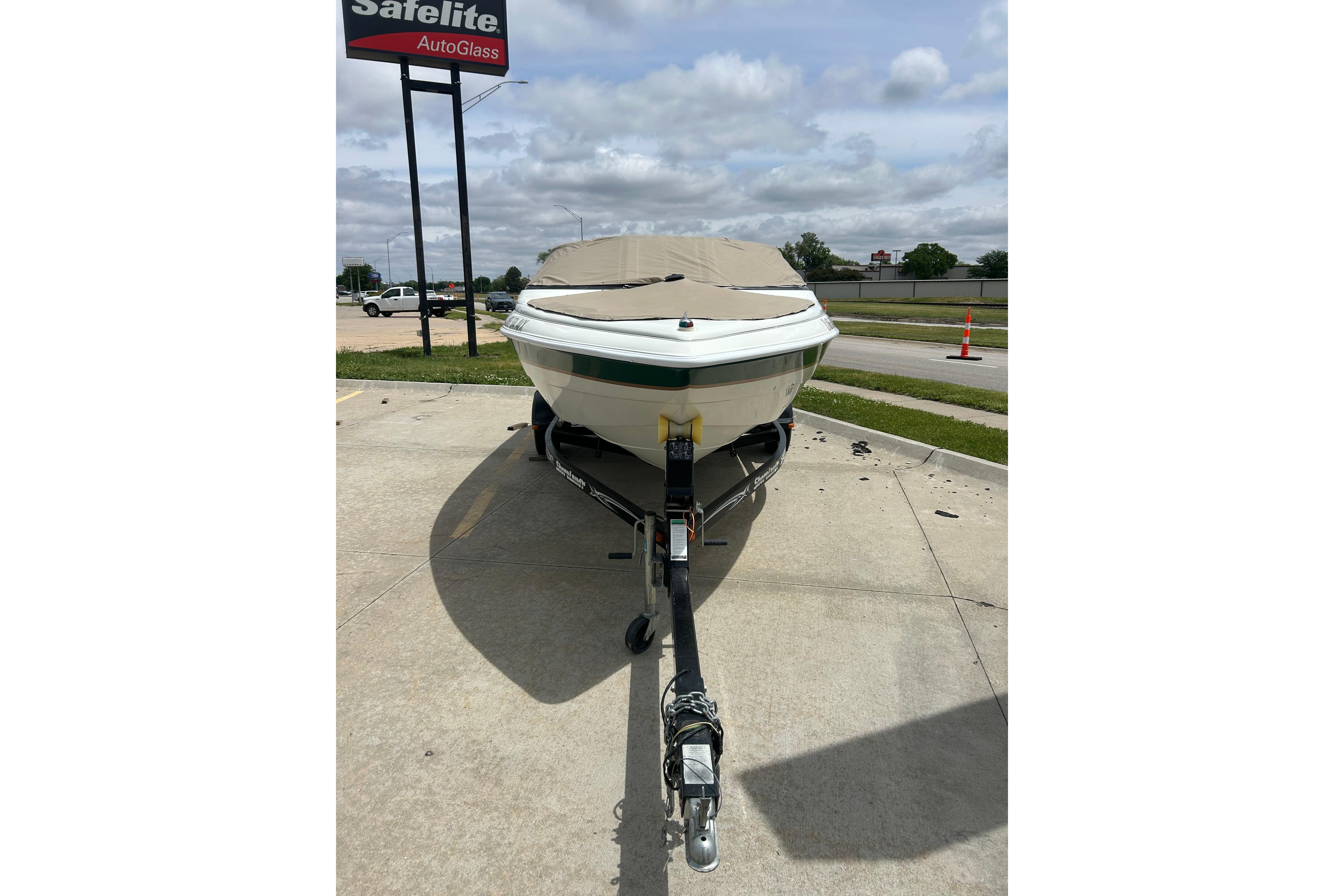 2000 Starcraft 1810 boat on trailer, parked near Safelite AutoGlass sign.
