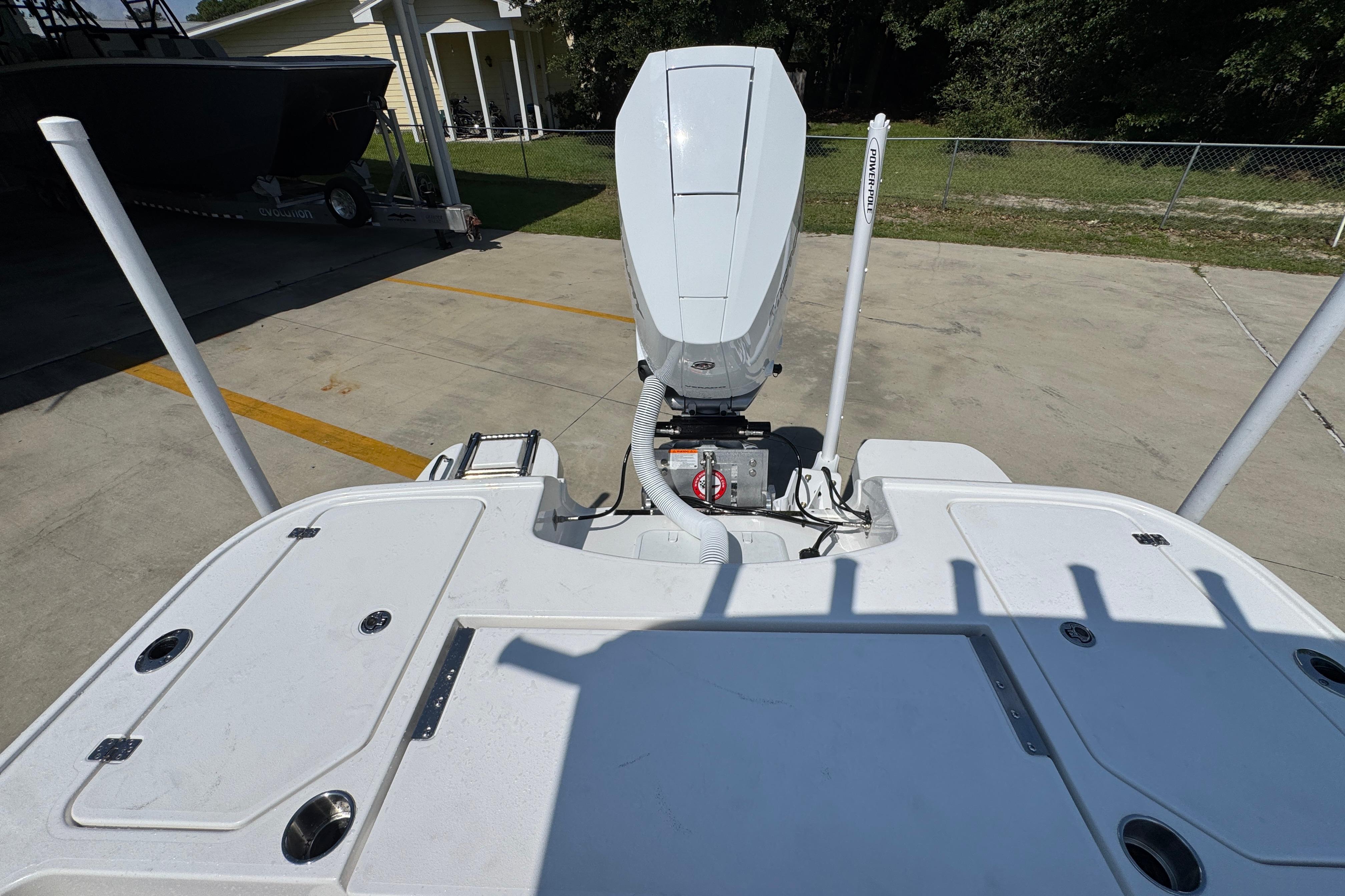 2027 Caymas 26 HB boat stern view with outboard motor in a driveway.