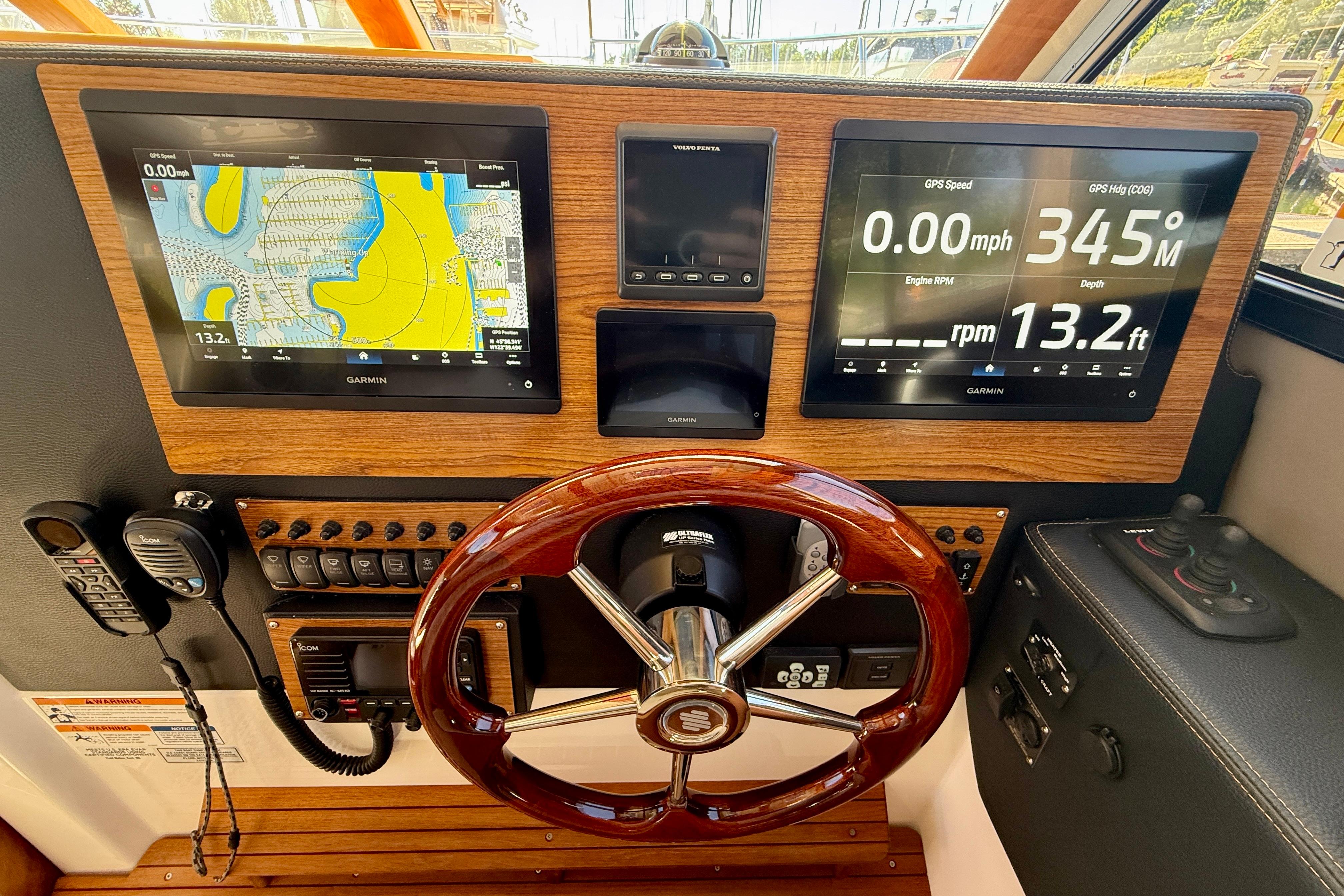 2023 Cutwater C-30 Sedan helm with Garmin navigation displays and wooden steering wheel.