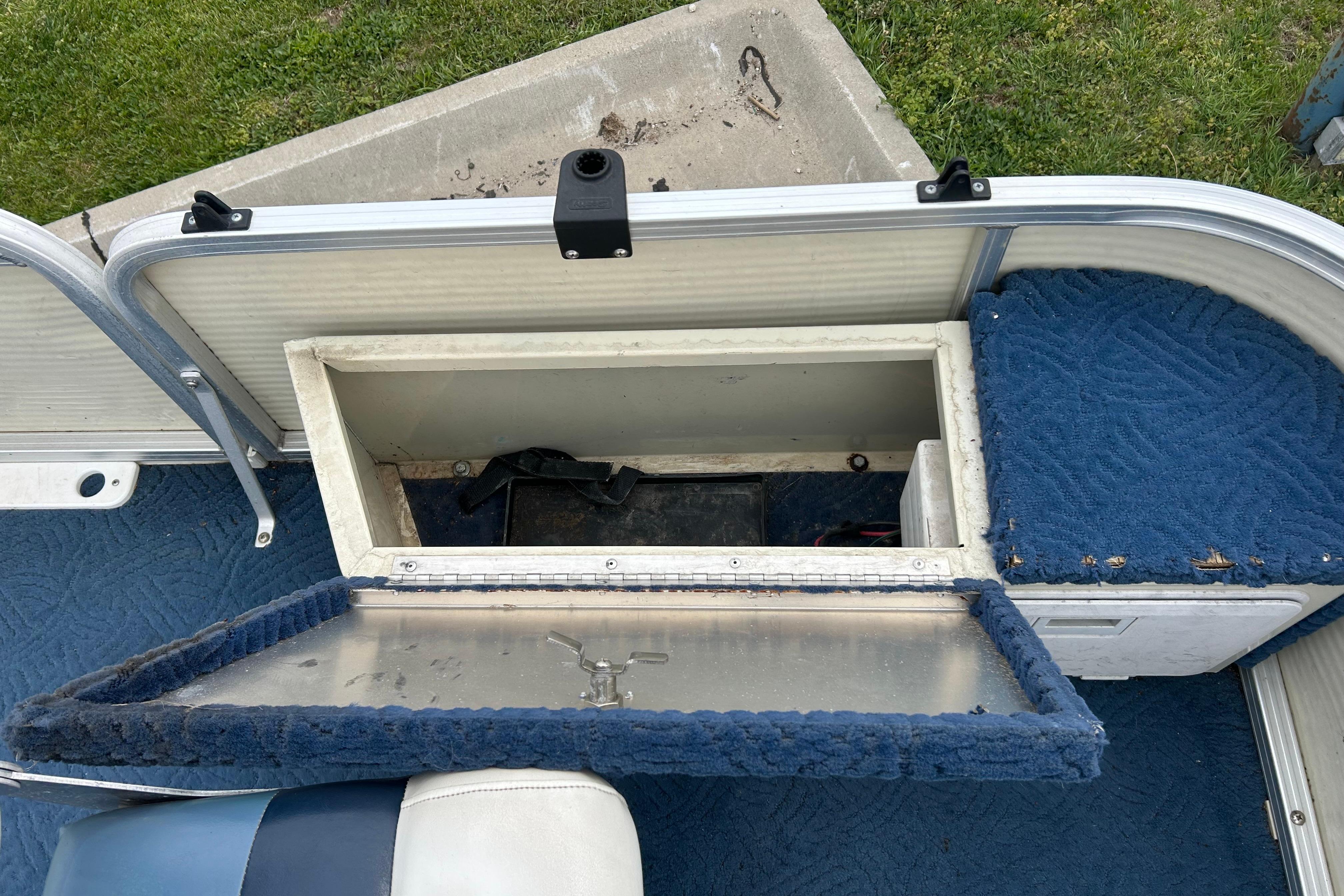 Open storage compartment on a 2002 Lowe Trinidad 200 boat with blue carpet interior.