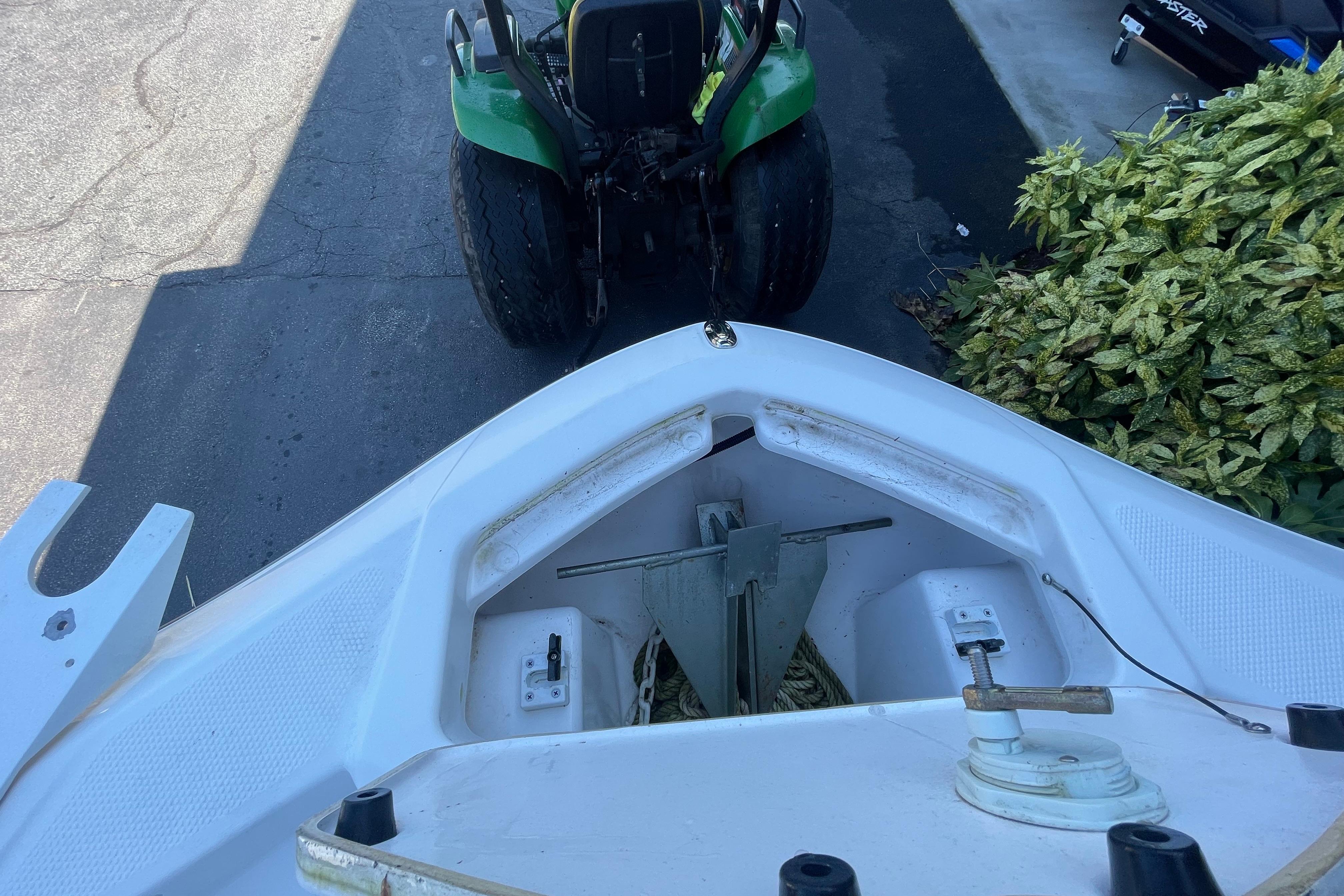 2021 Yamaha Boats 195 FSH Sport bow with anchor storage, near a green tractor.