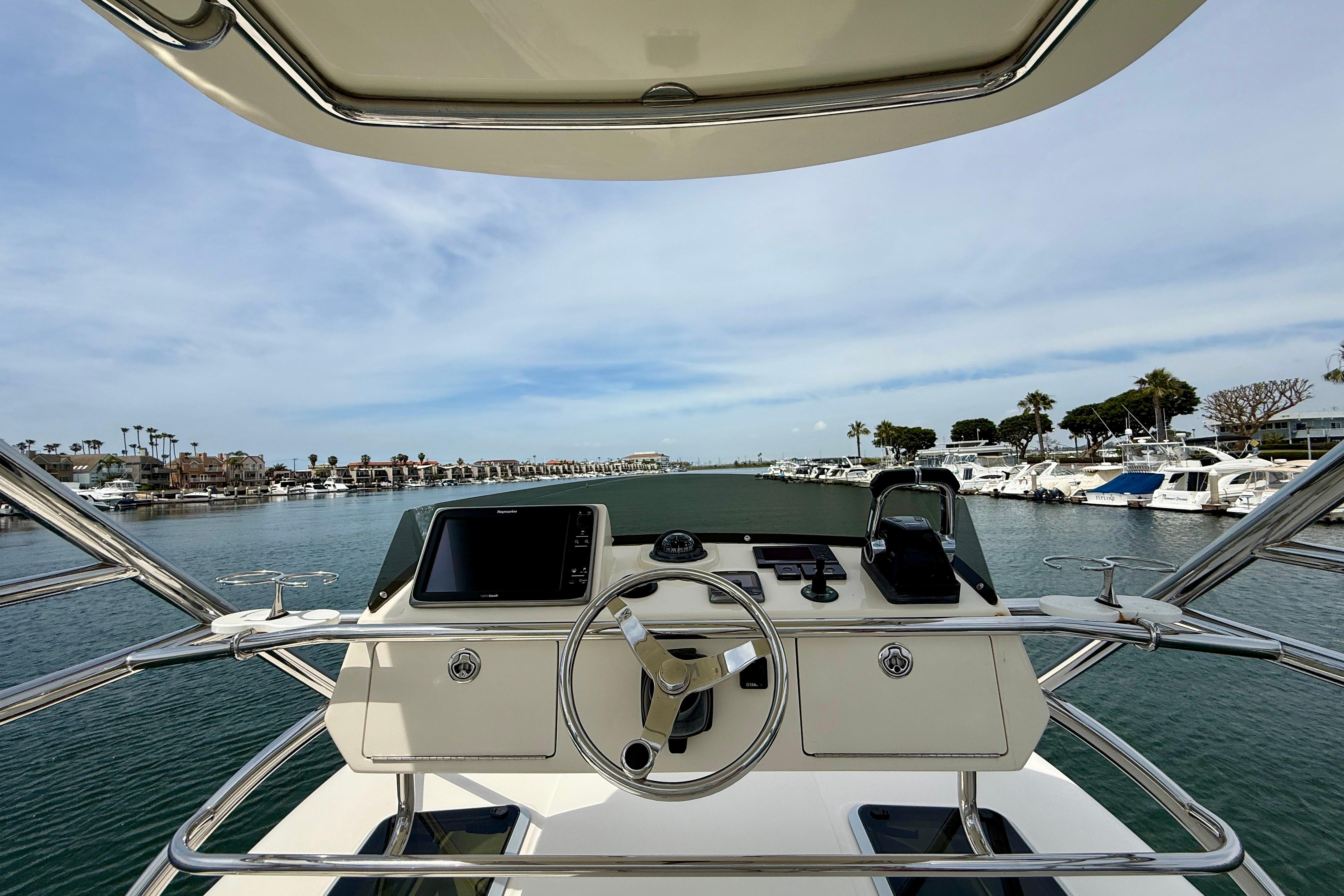 Helm view of 2012 Pursuit OS 345 Offshore boat in a marina setting.
